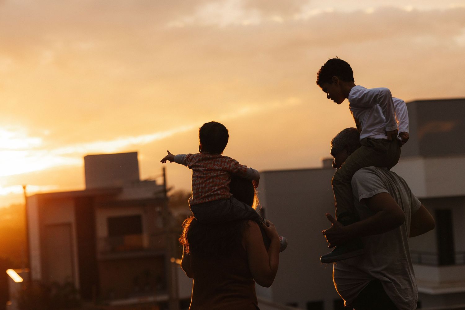 Silhouettes against a golden sunset sky with buildings in the background.