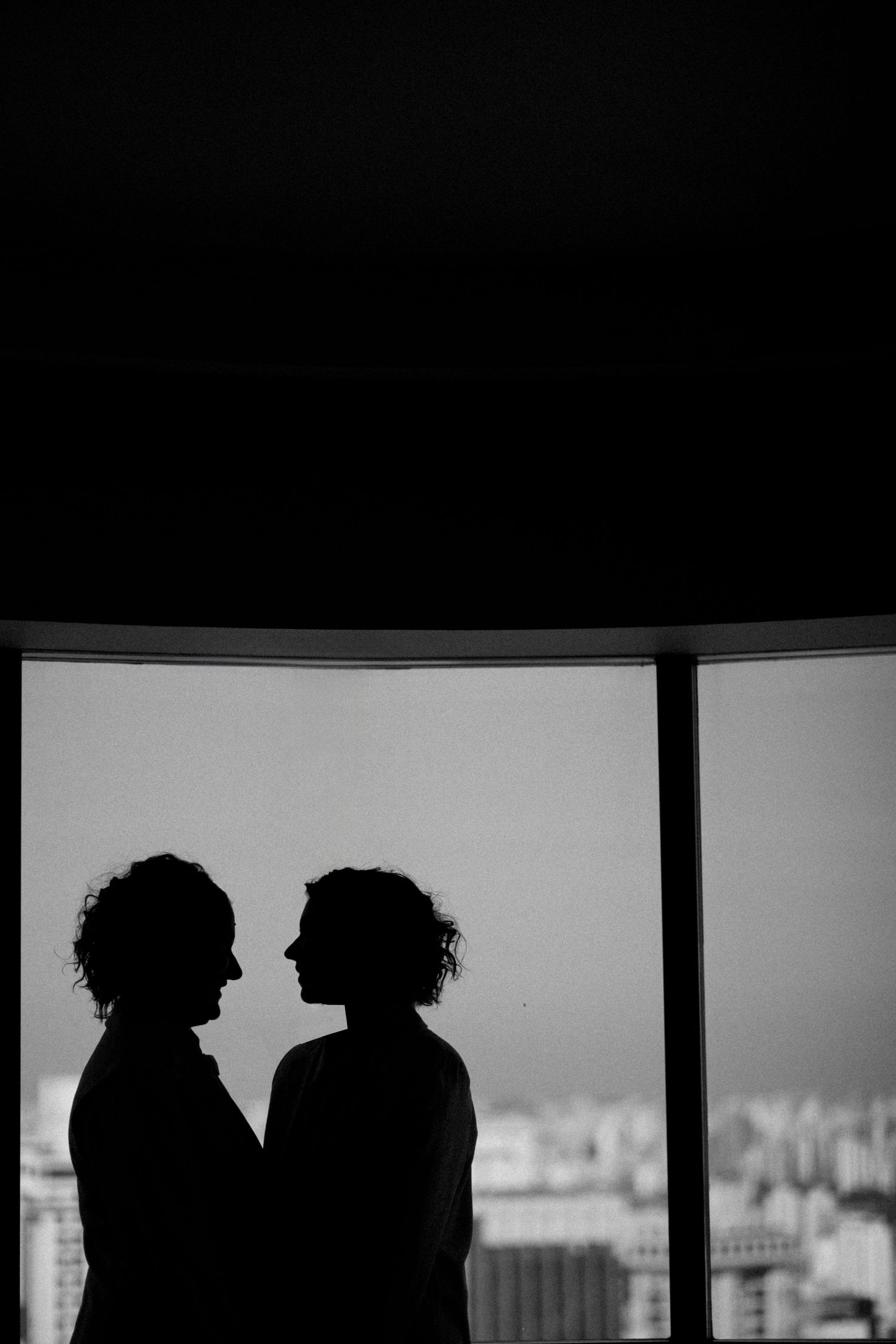 Silhouetted figures with curly hair against a bright window create a dramatic black and white contrast.