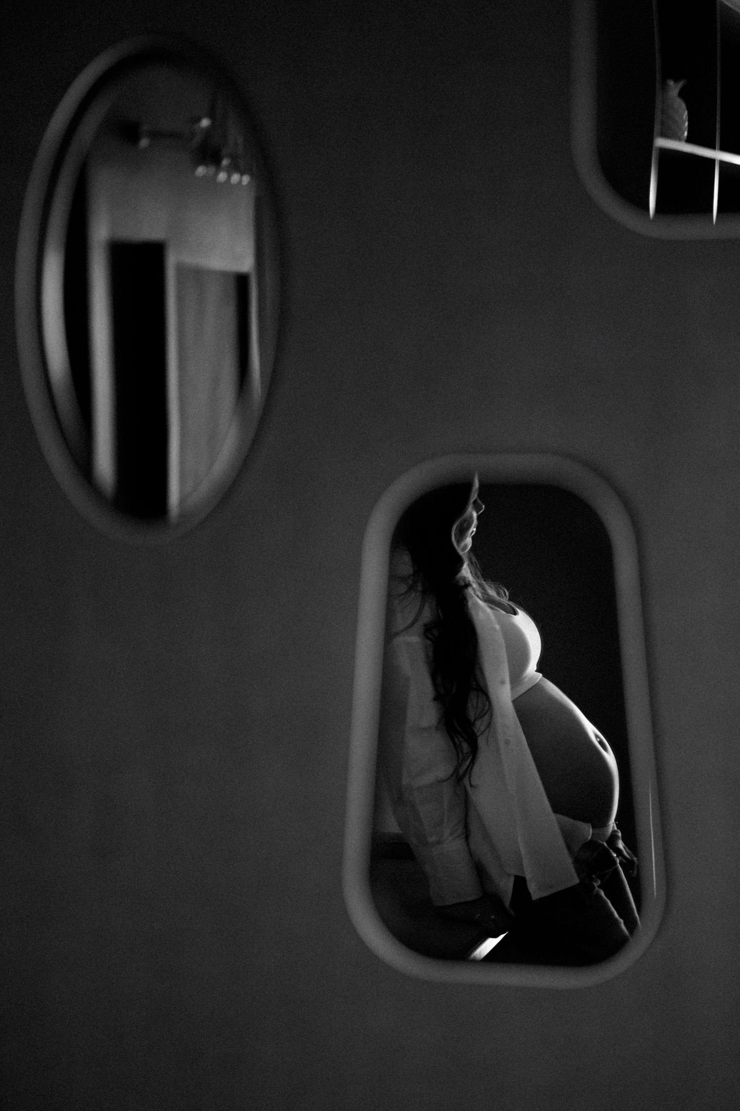 Artistic black and white photographs through oval window frames creating dramatic shadows.