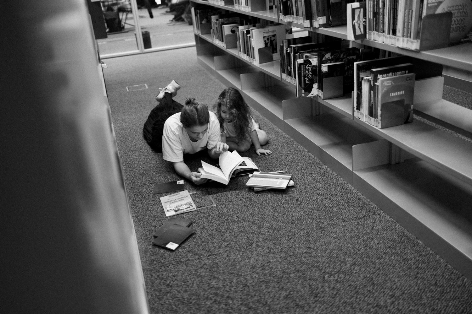 People relaxing and reading on the floor of a library or bookstore.