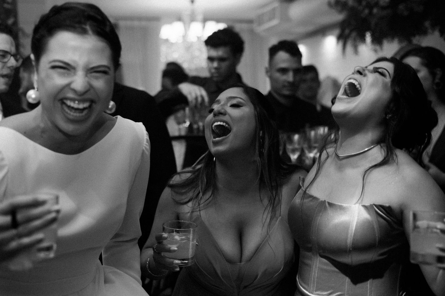Black and white candid shots capturing genuine laughter and joy at wedding reception.