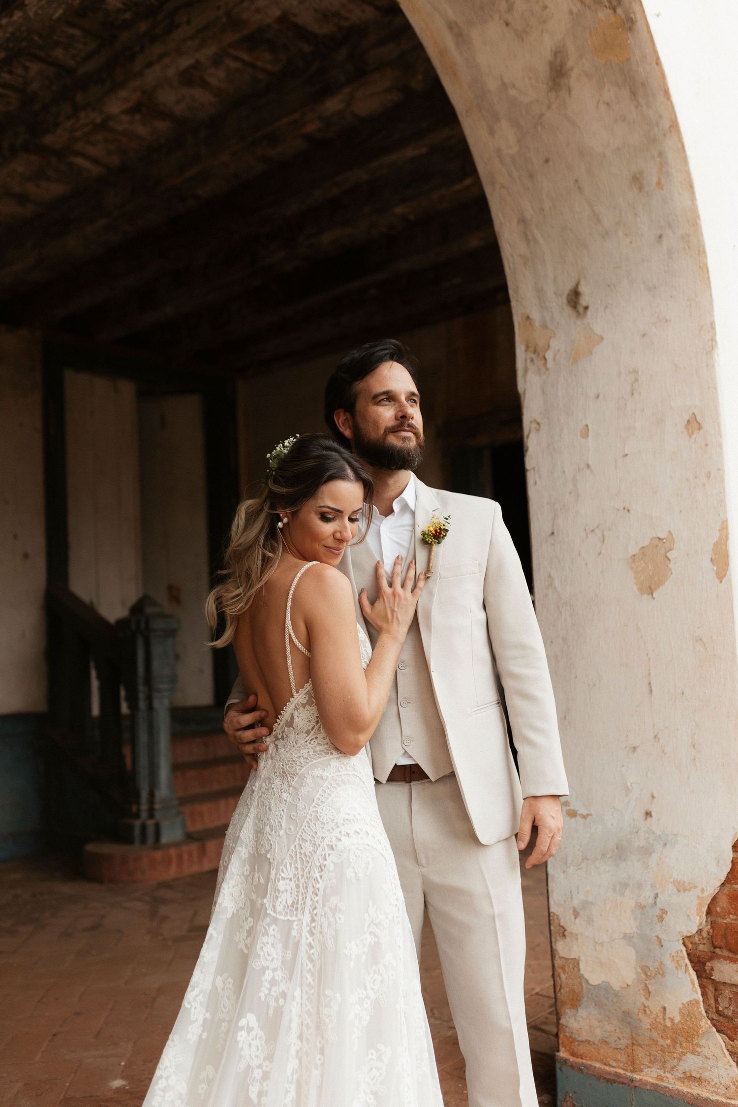 Couple shares romantic first look moment under weathered Spanish colonial arches.