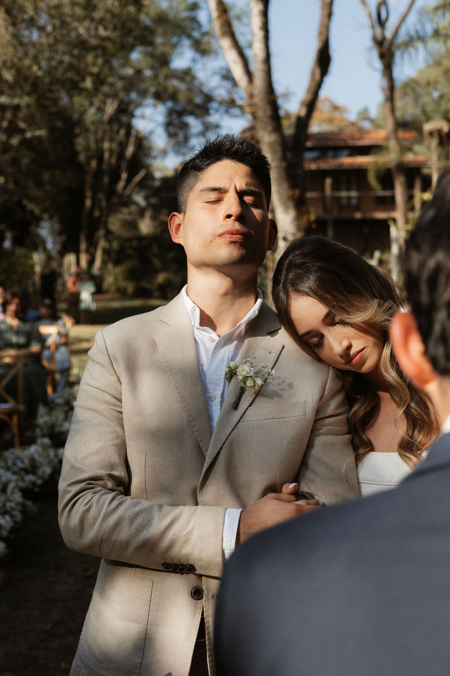 A romantic wedding couple embraces during their outdoor photo session in beige and white attire.