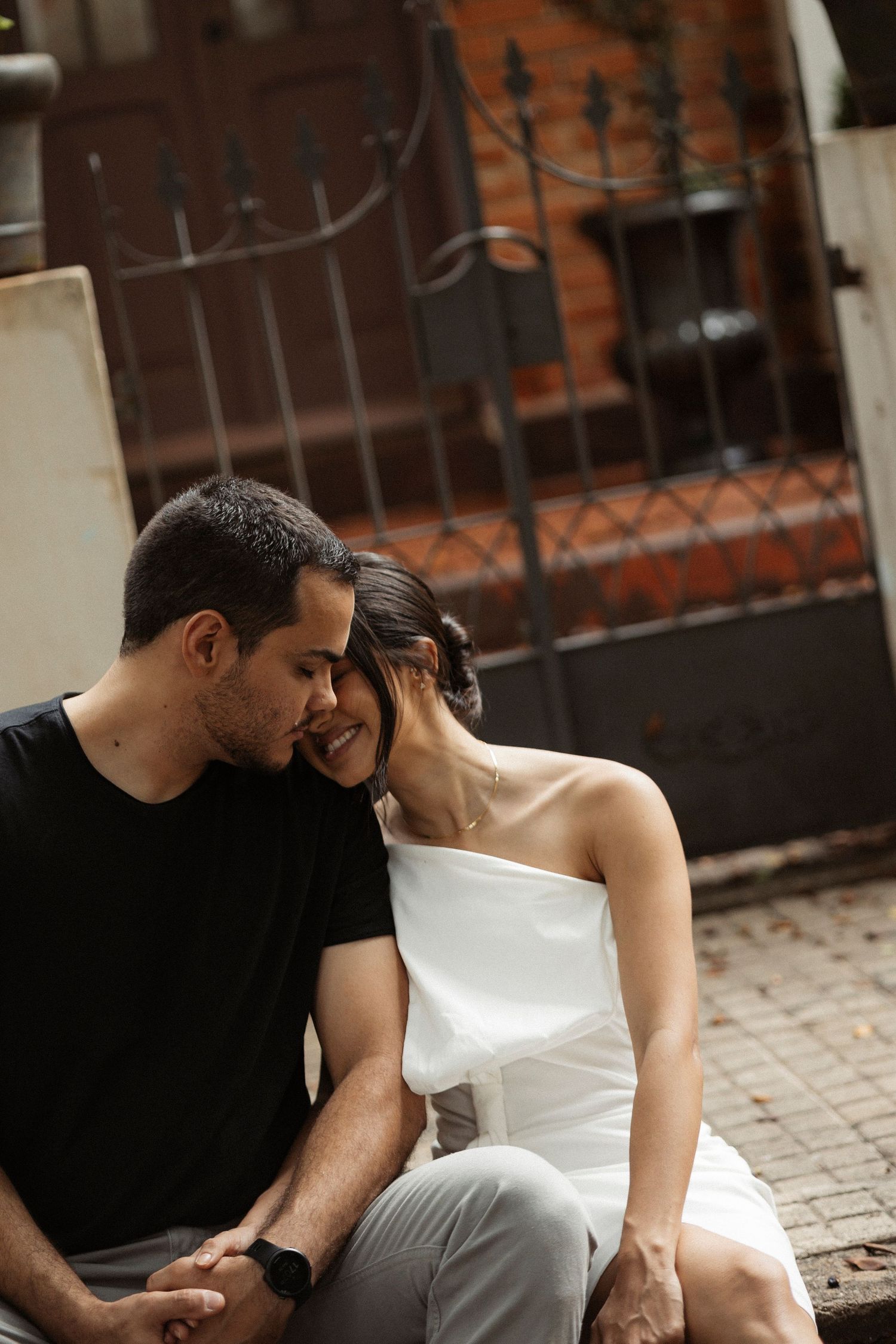 Couple in black and white attire sharing intimate moments on a brick patio.