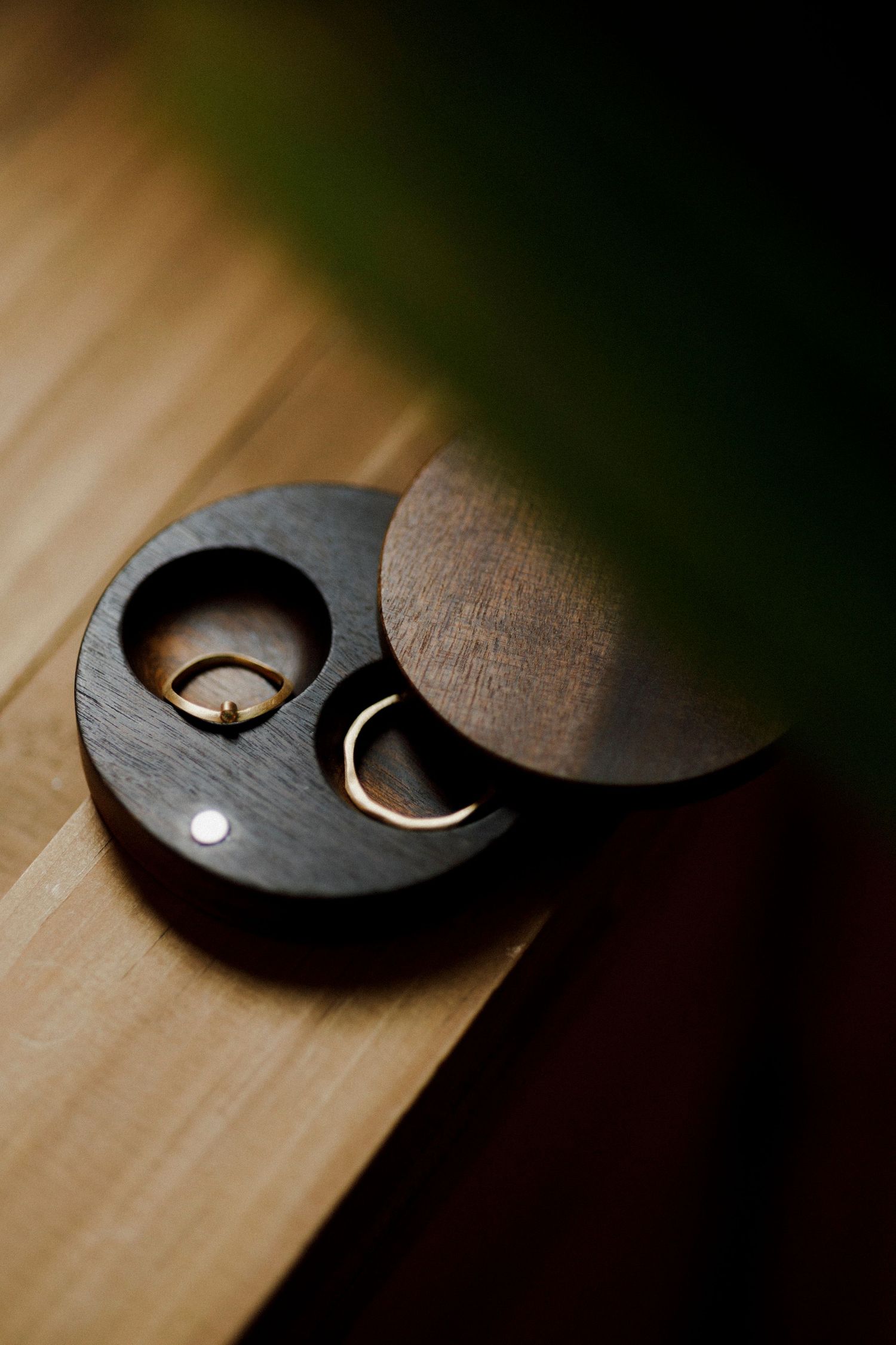 Close-up of wooden wedding ring boxes with curved designs on wooden surface.