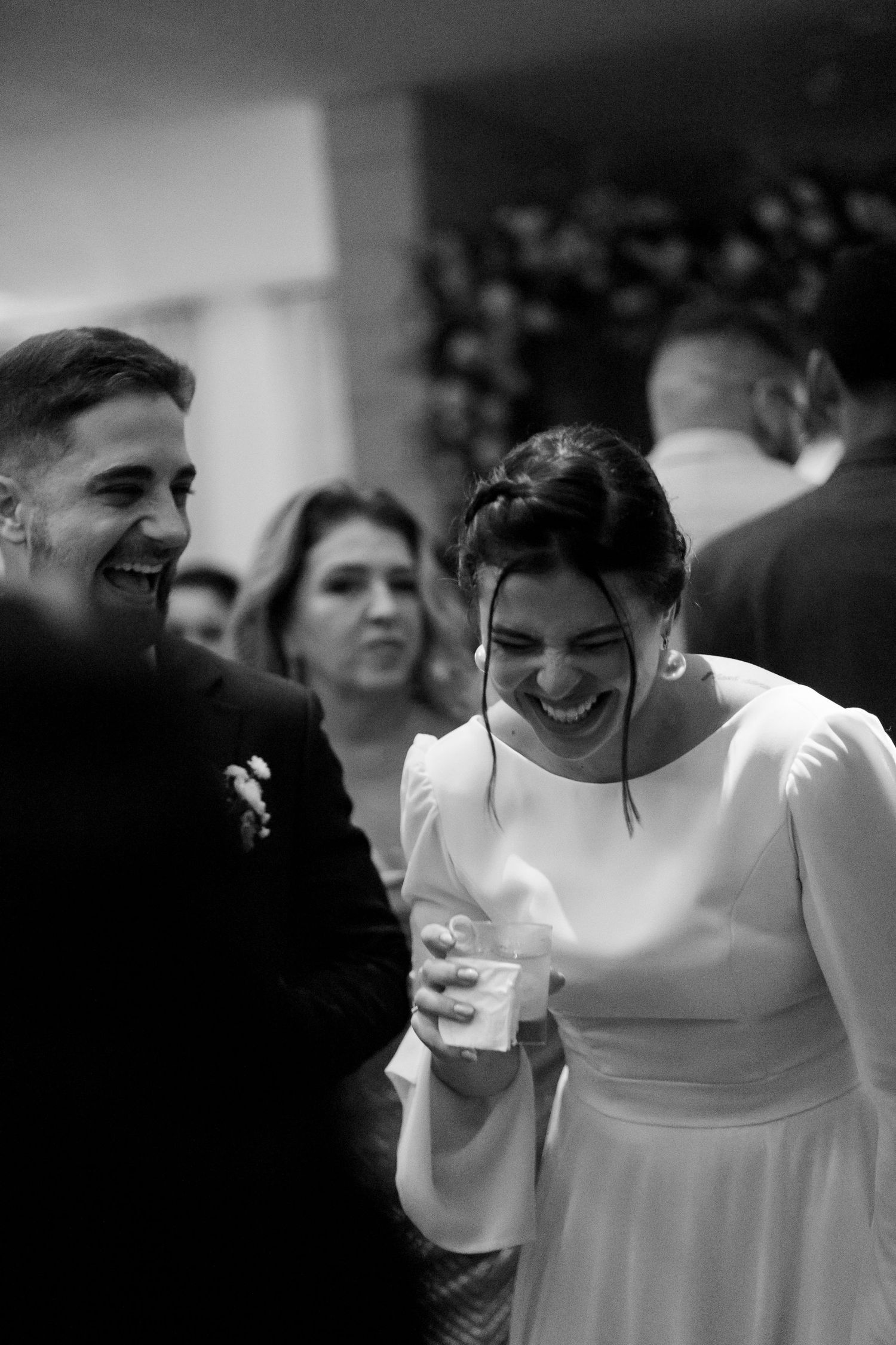 Black and white candid shots of wedding guests enjoying drinks and conversation at reception.