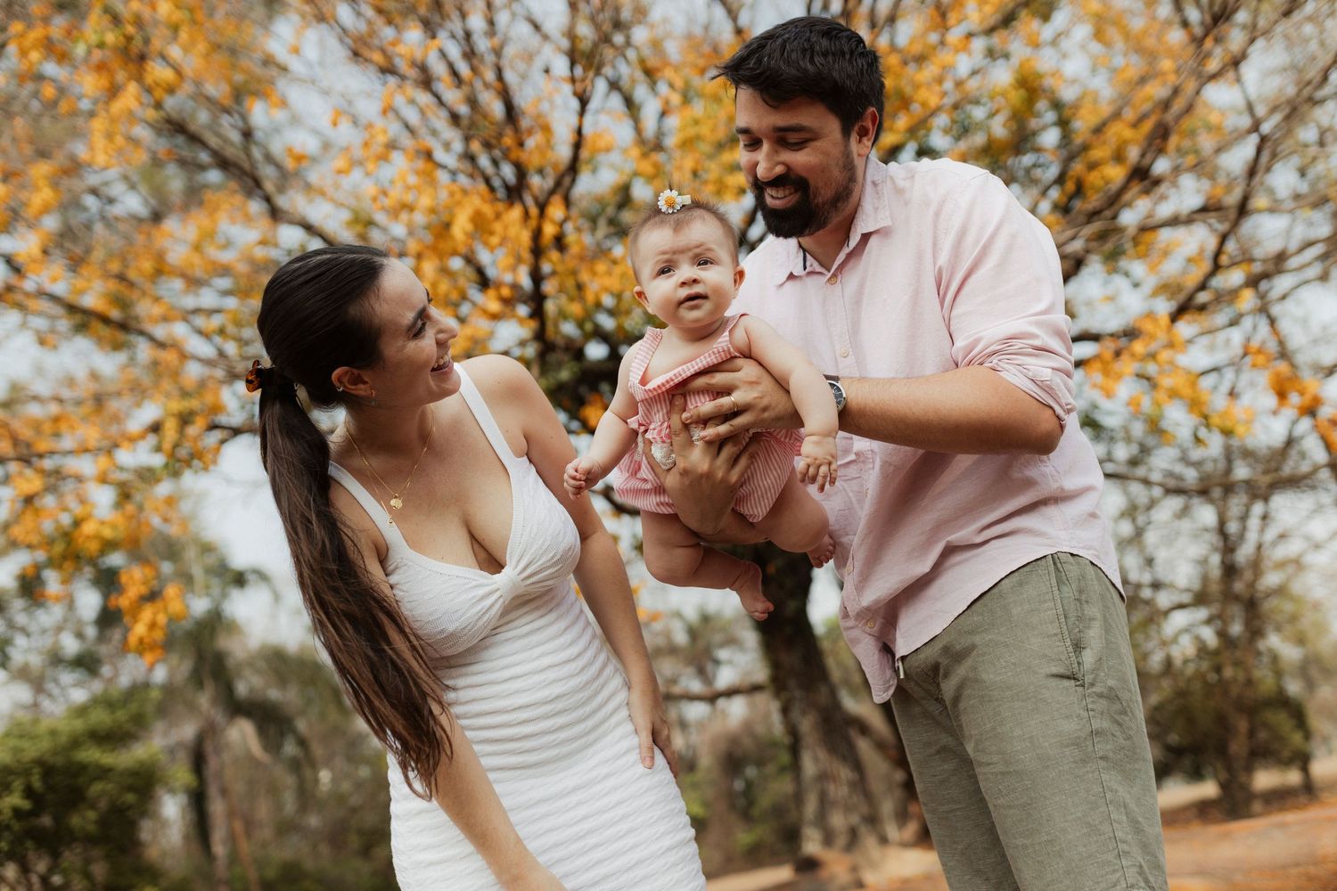 A couple shares joyful moments together under golden autumn trees in a park setting.