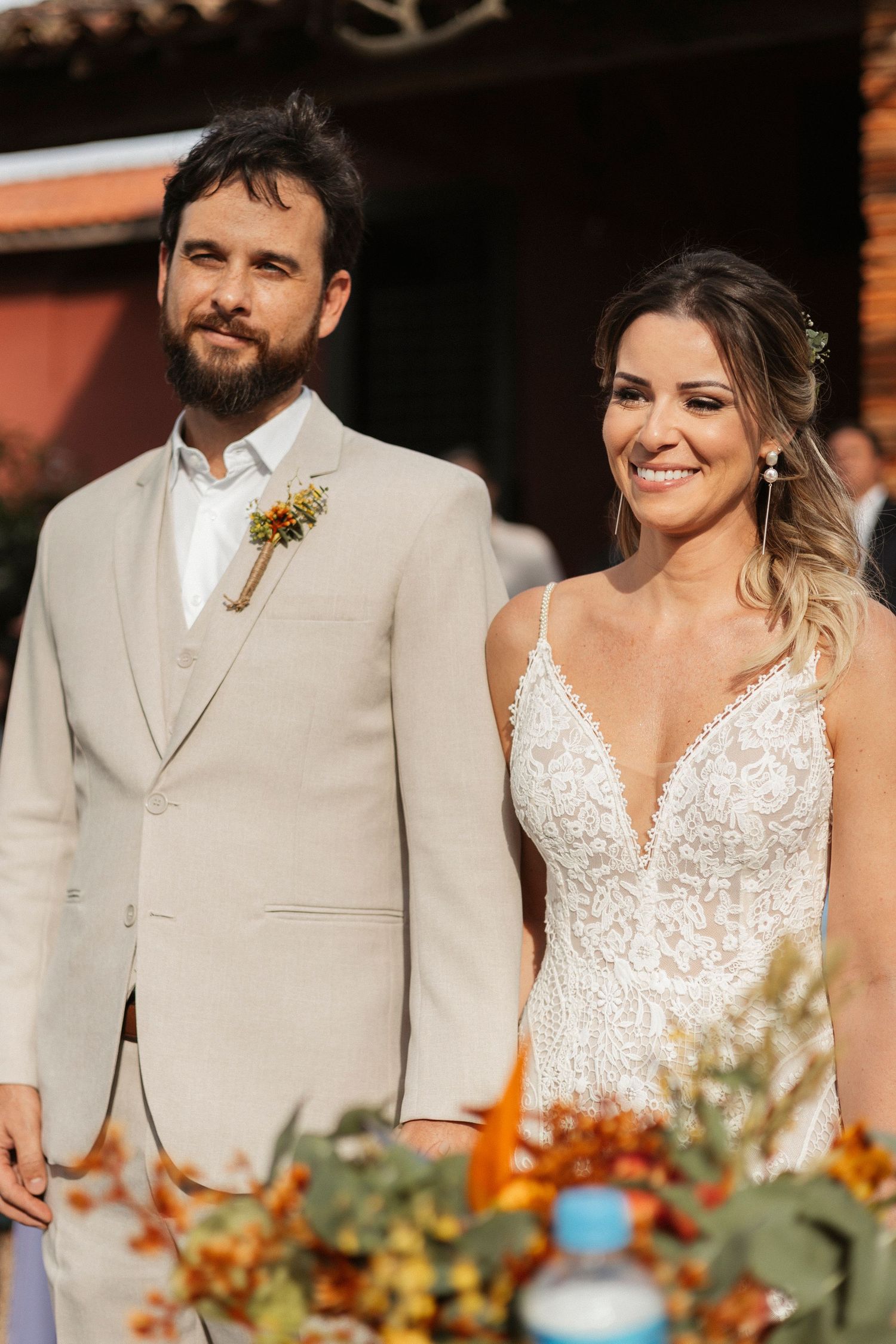 Wedding couple sharing joyful moments during outdoor ceremony with floral decorations.