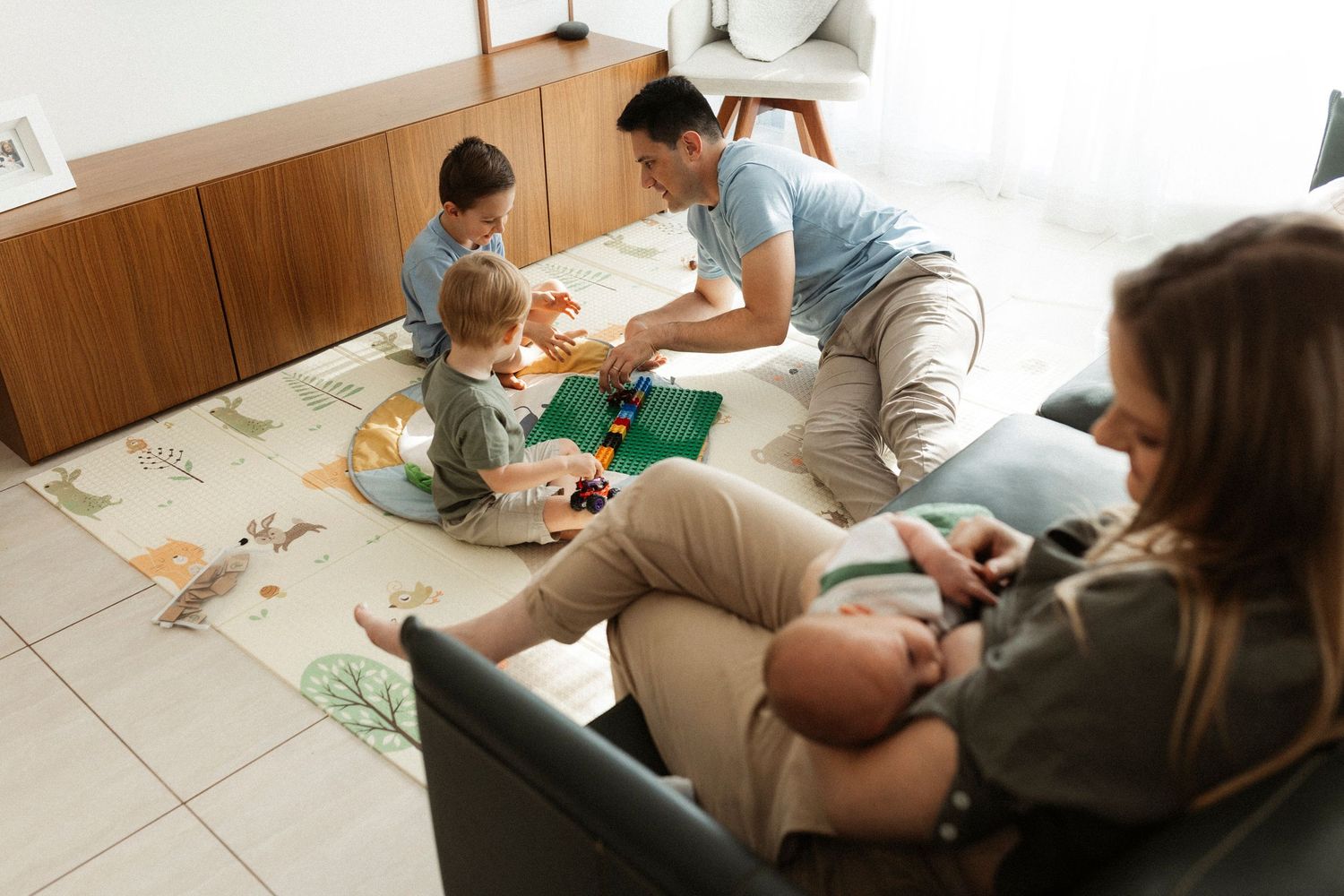 Children lie on white sheets during a cozy indoor photoshoot session.
