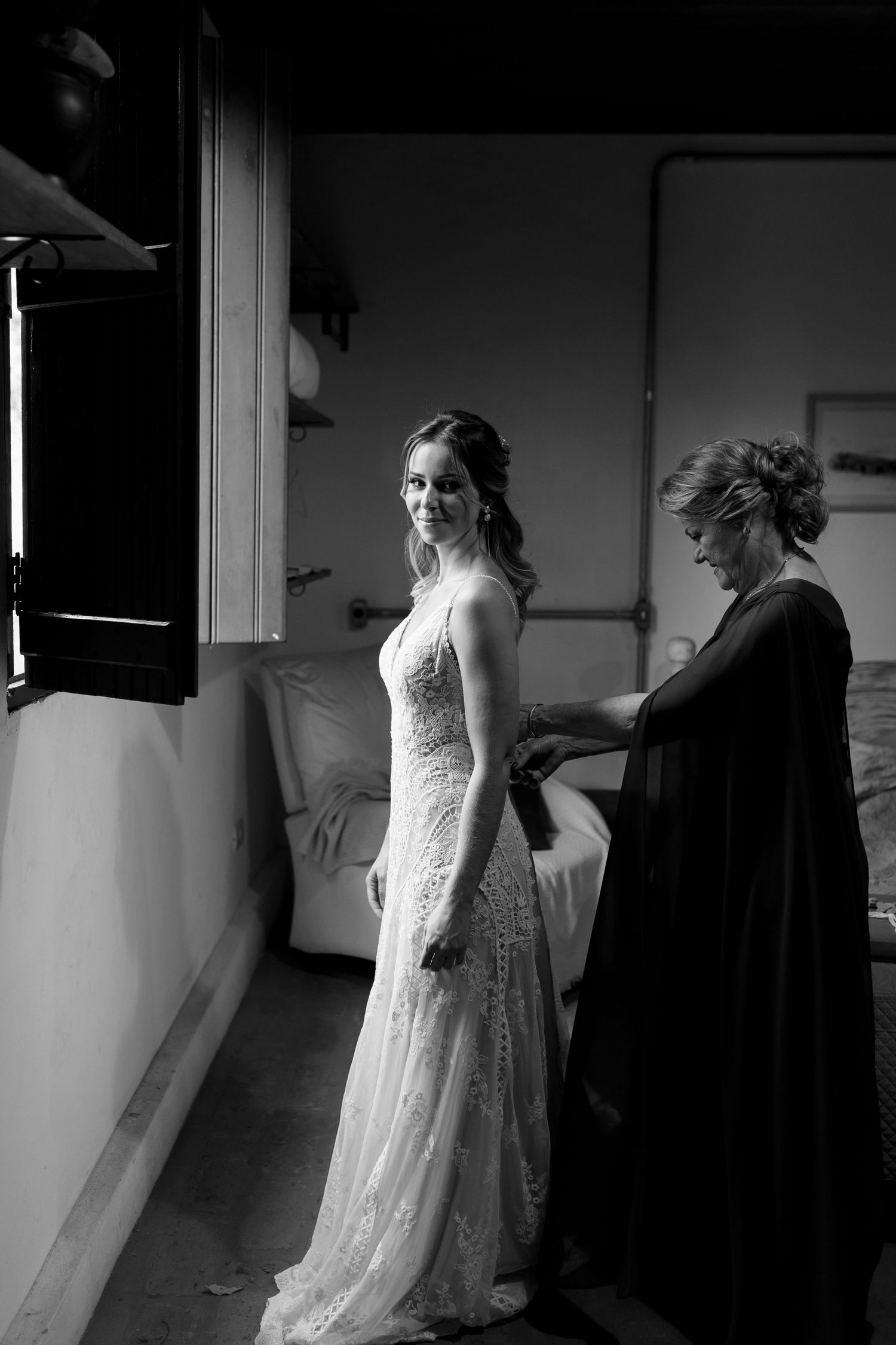 Wedding dress preparation scene captured in dramatic black and white lighting.