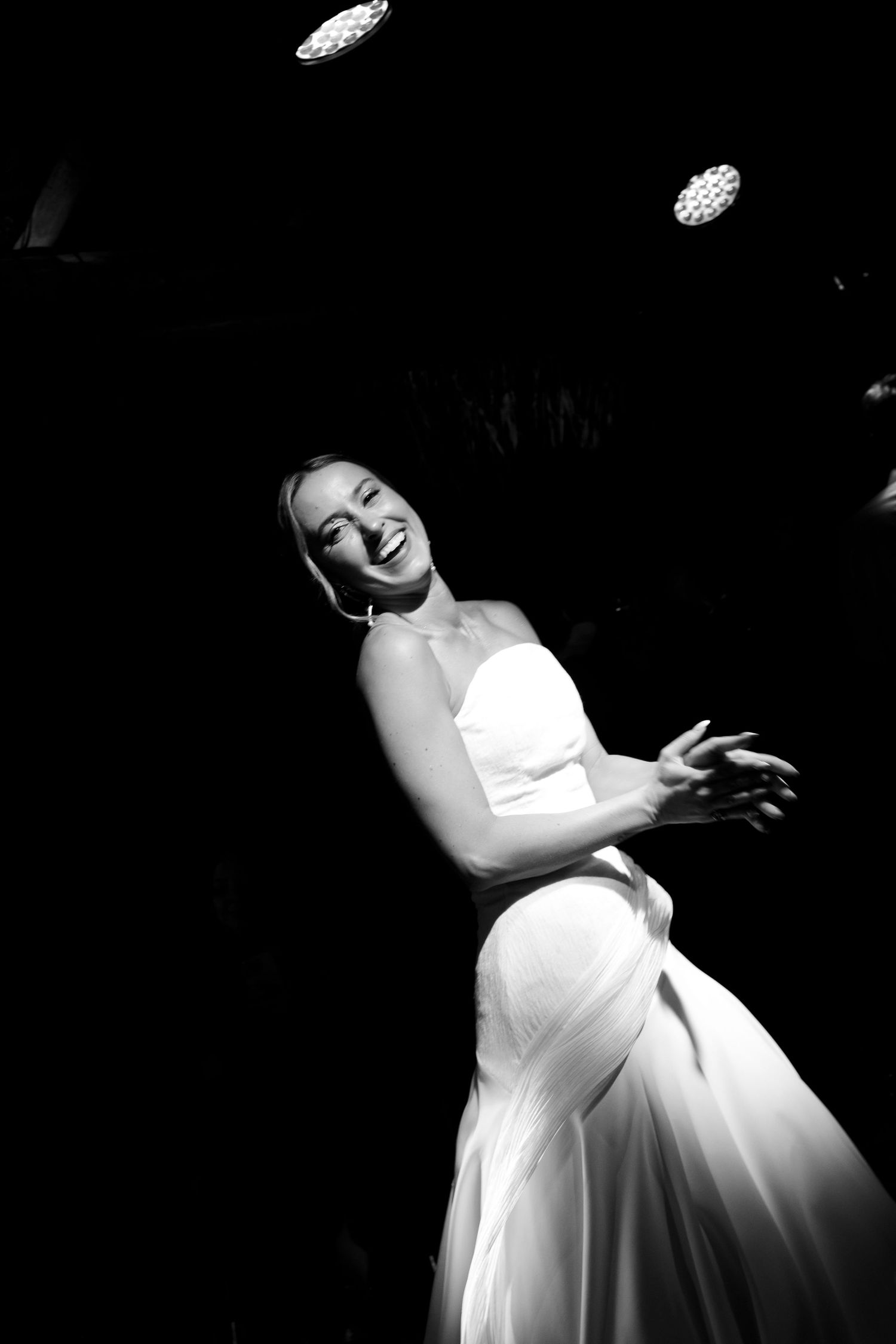 An artistic black and white photo of a white wedding dress in dramatic lighting.