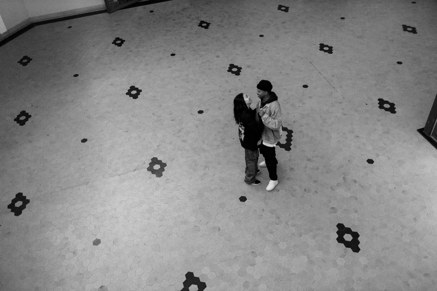 Black and white overhead view of people on a patterned floor.