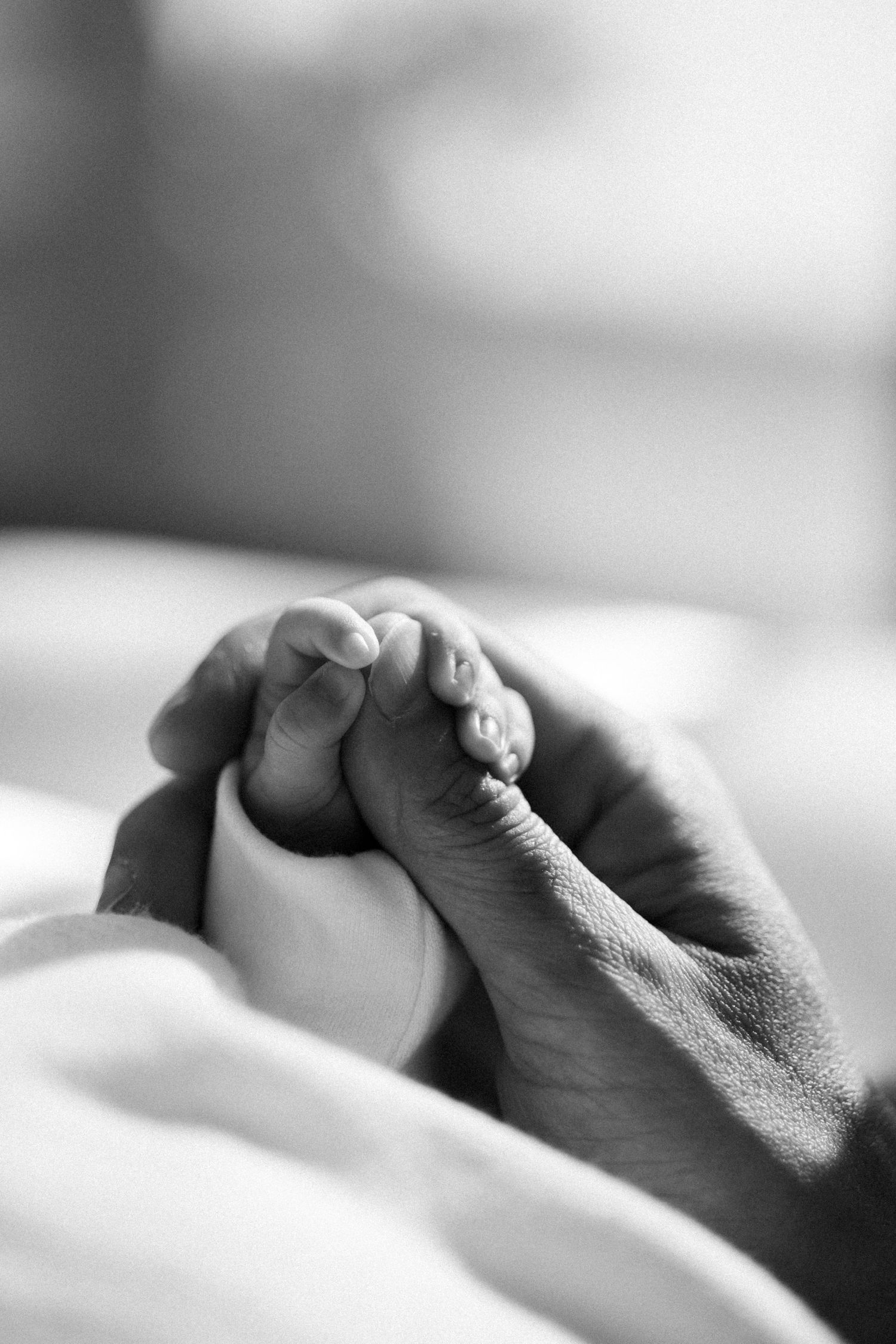 Close-up sequence of two hands gently clasping together in black and white.