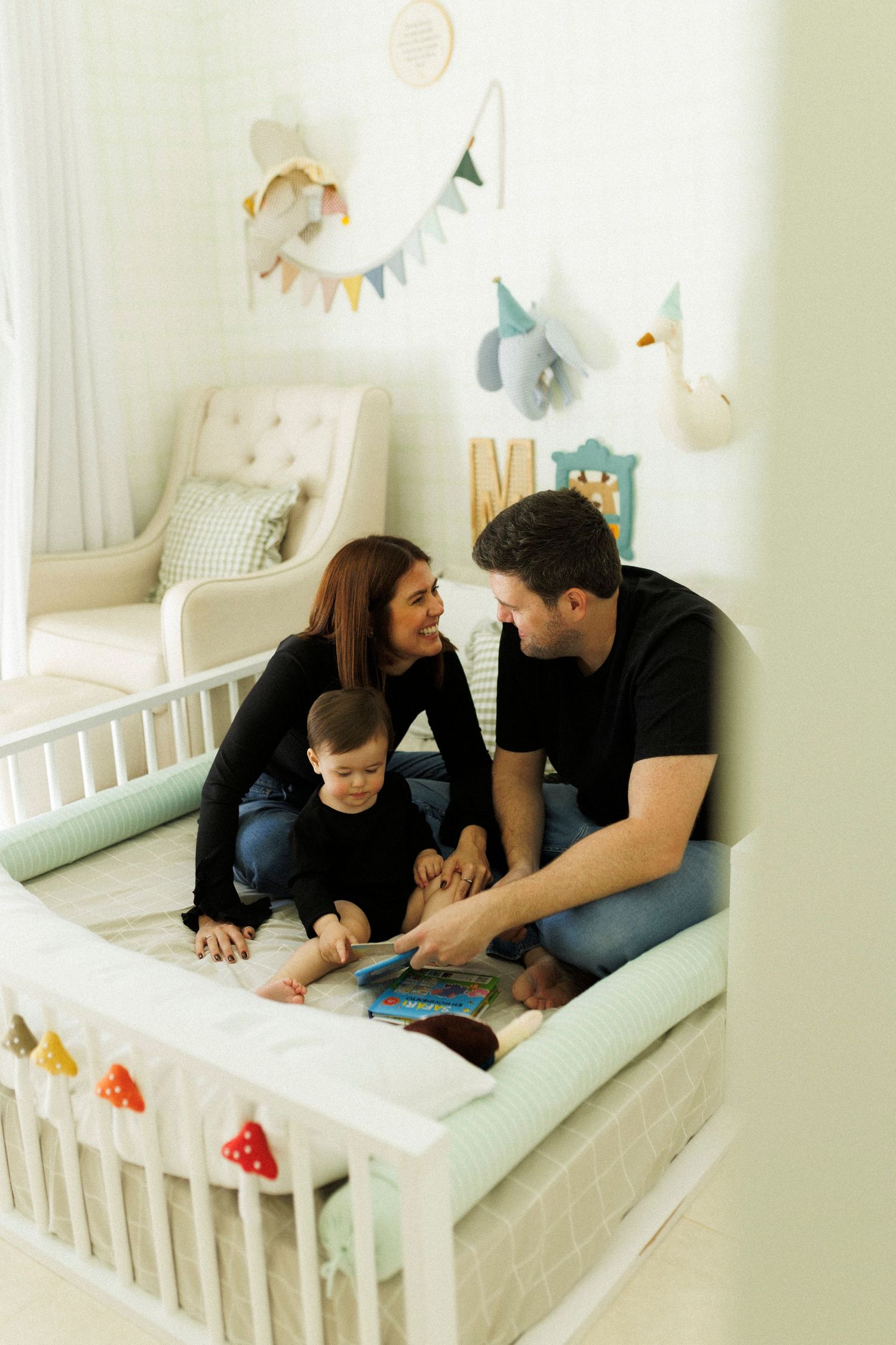 Family shares tender moments together in a nursery decorated with soft colors and bunting.