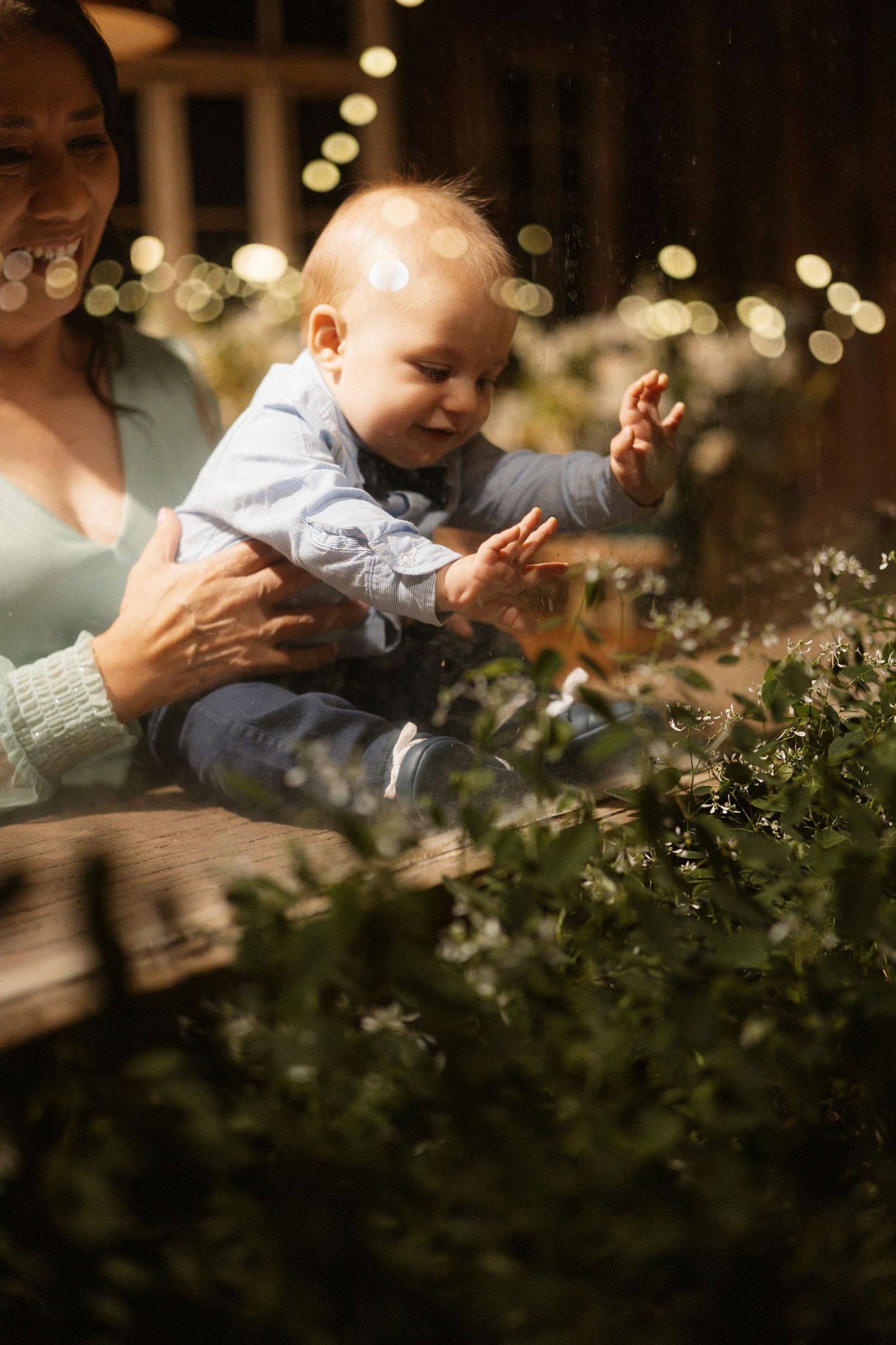 A baby plays joyfully among blooming flowers in soft evening light.