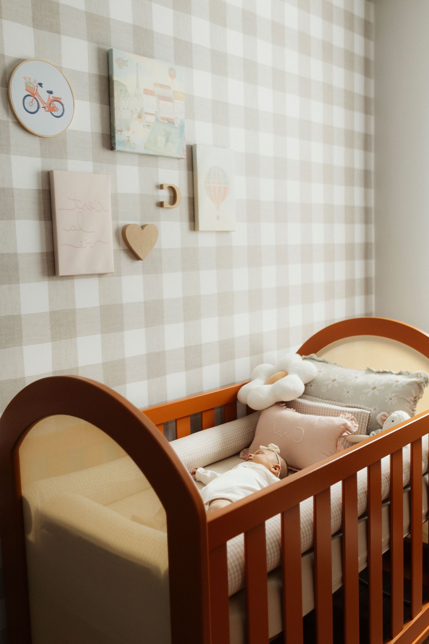 A nursery room with gingham wallpaper and wooden crib decorated with wall art.