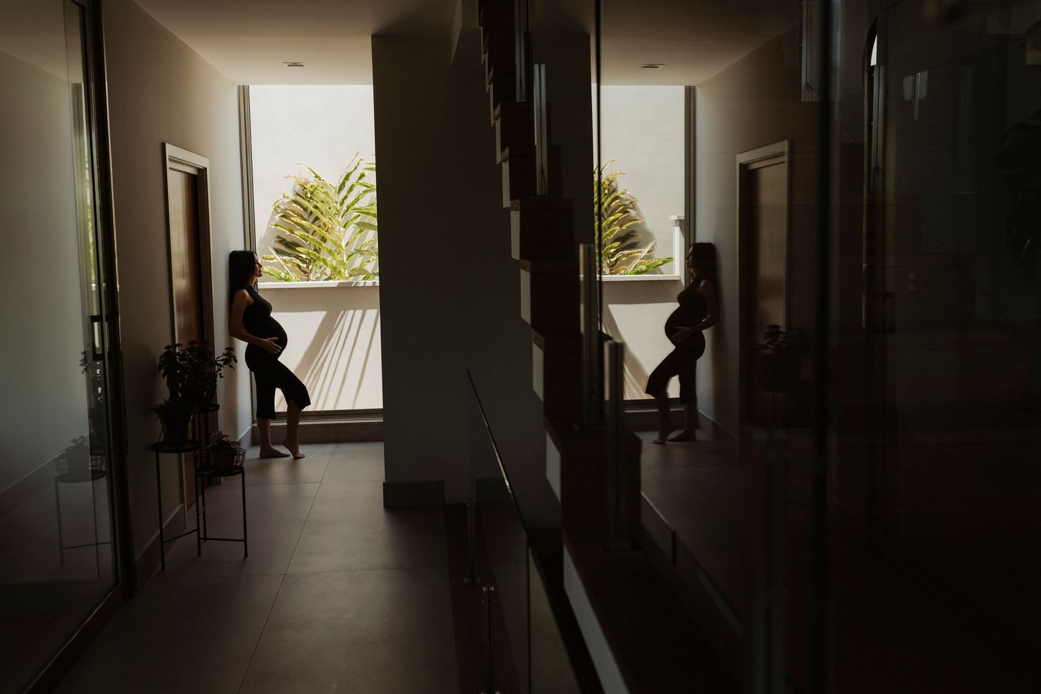 Silhouetted figures in modern corridor with window lighting.