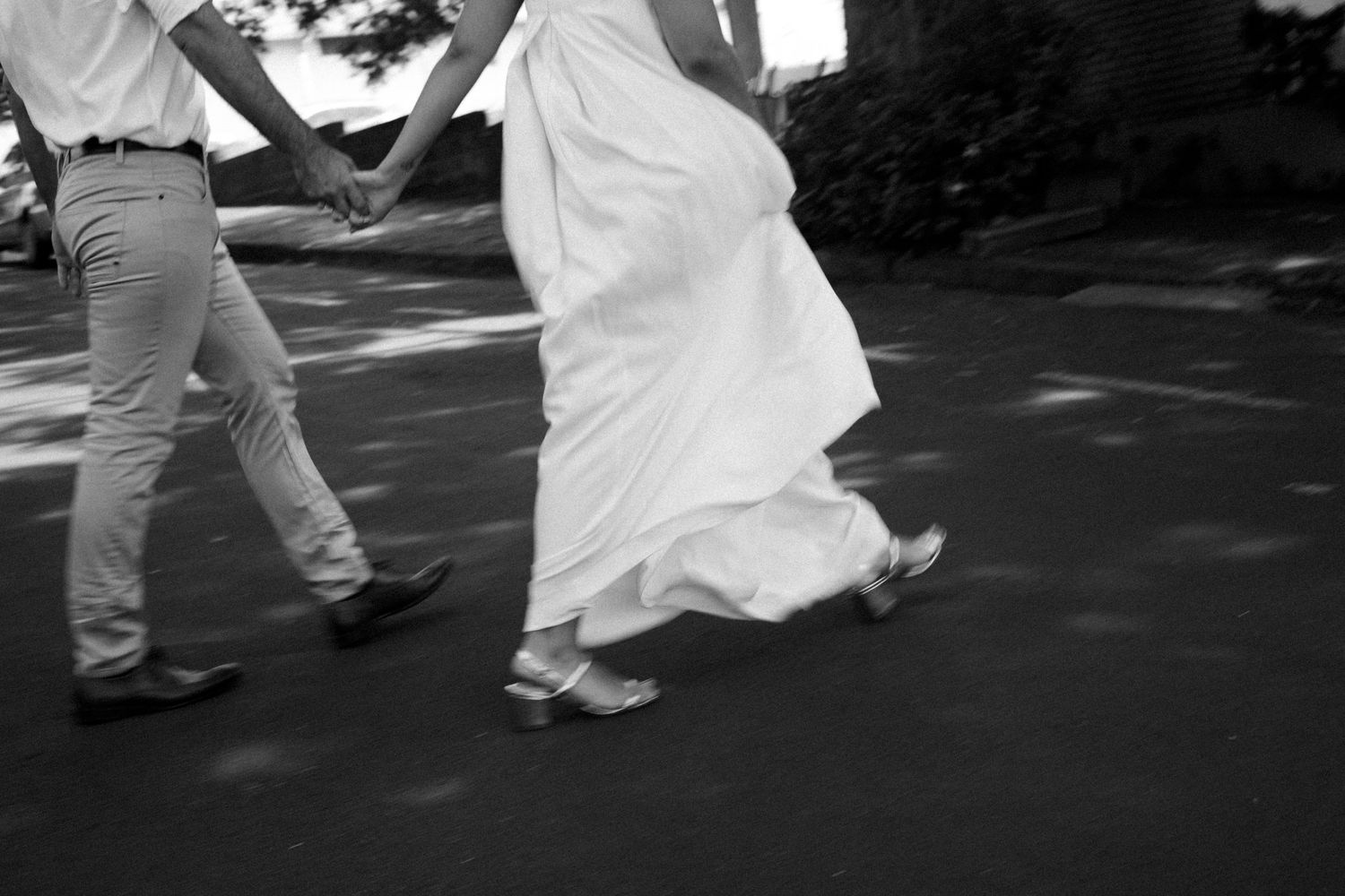 Dancing couple in white attire casting shadows on a sunlit path.