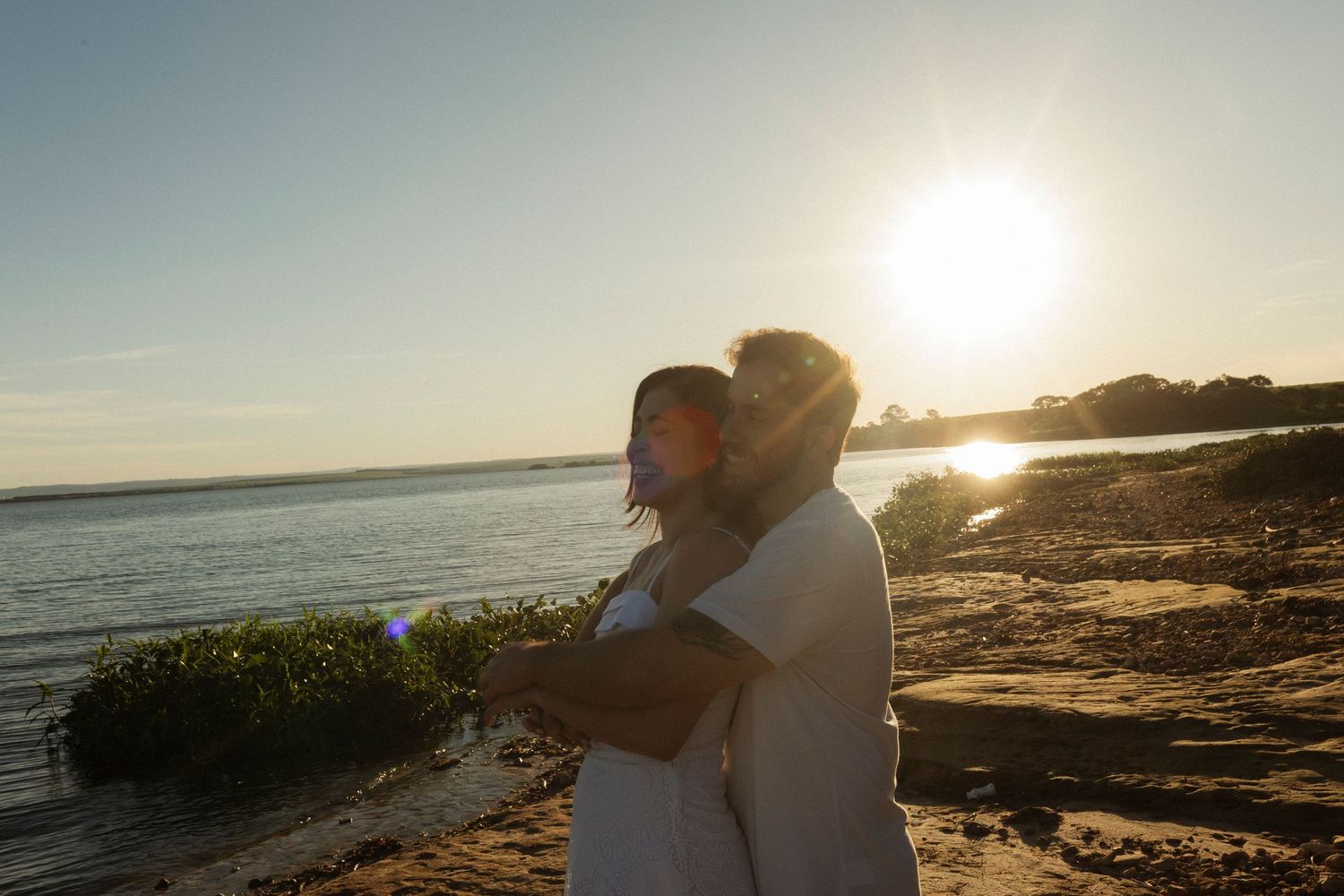 Romantic sunset beach photoshoot with silhouettes against golden ocean backdrop.