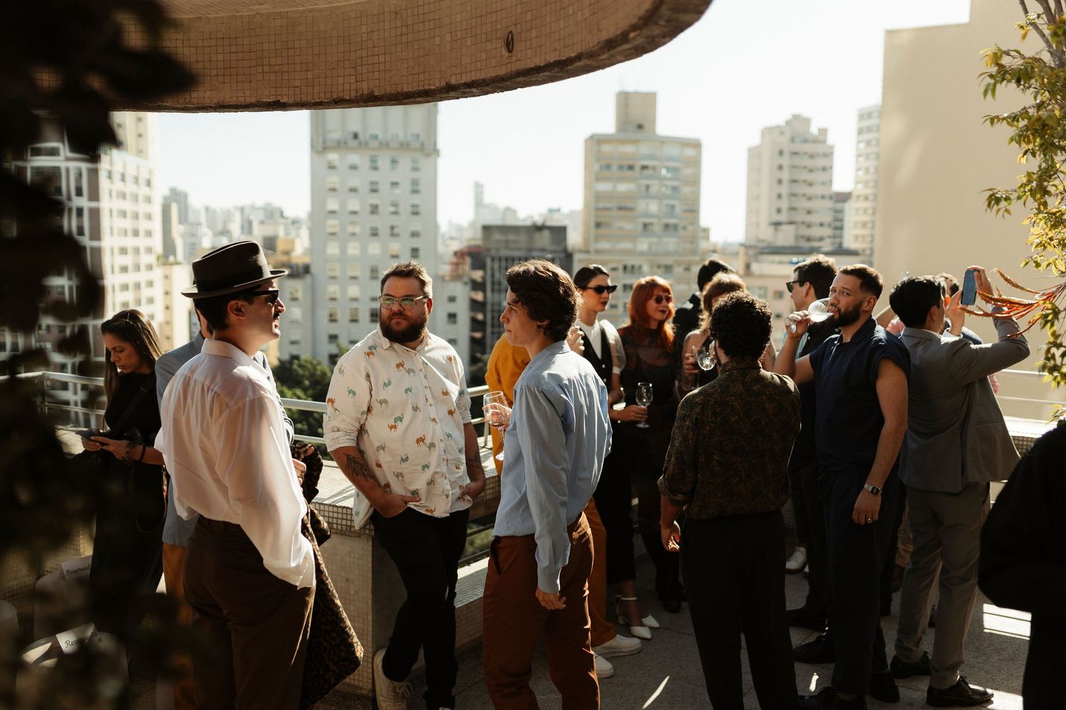 People mingling at an outdoor event with city buildings visible in the background.
