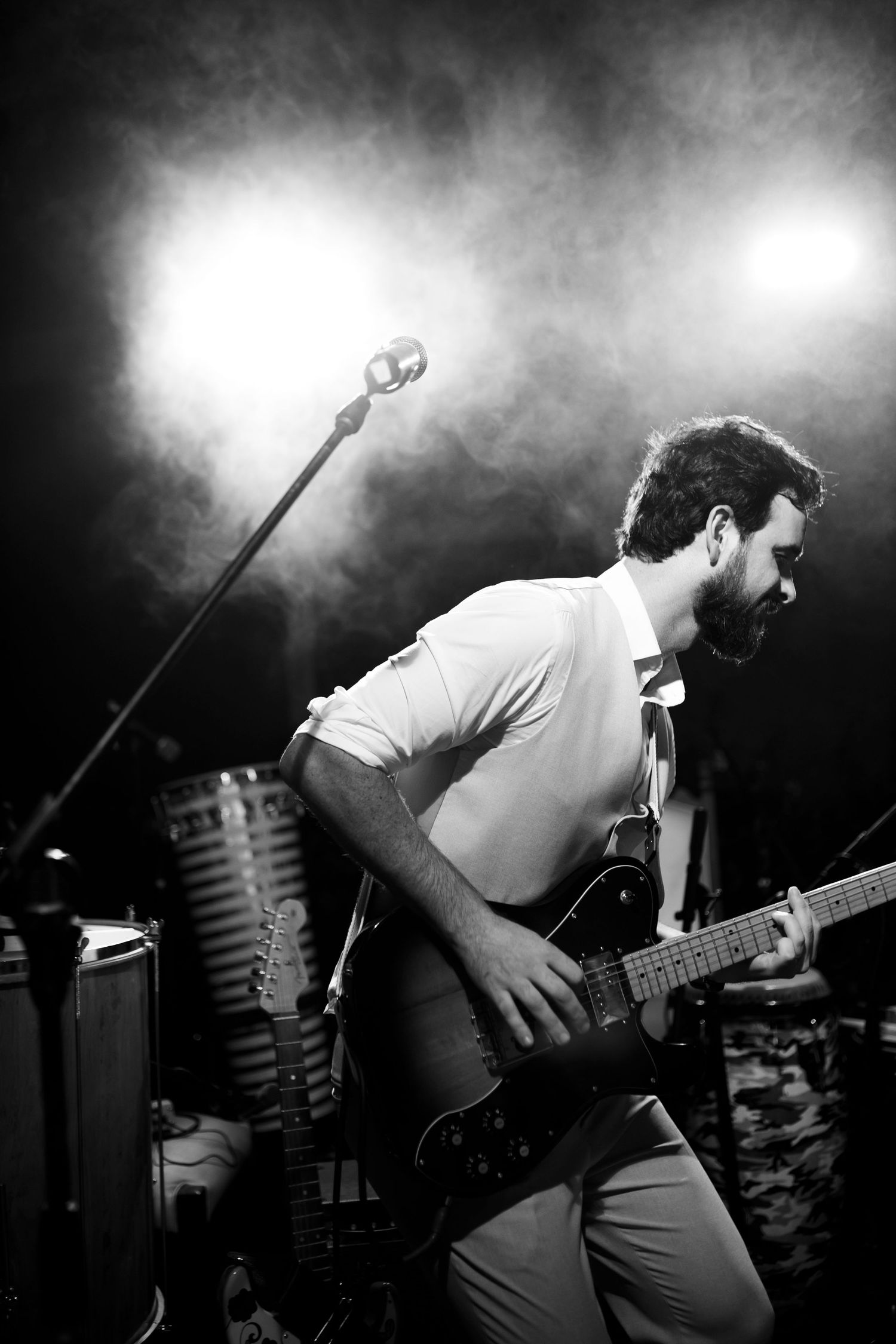 Dynamic black and white sequence of musician playing guitar on smoky stage.