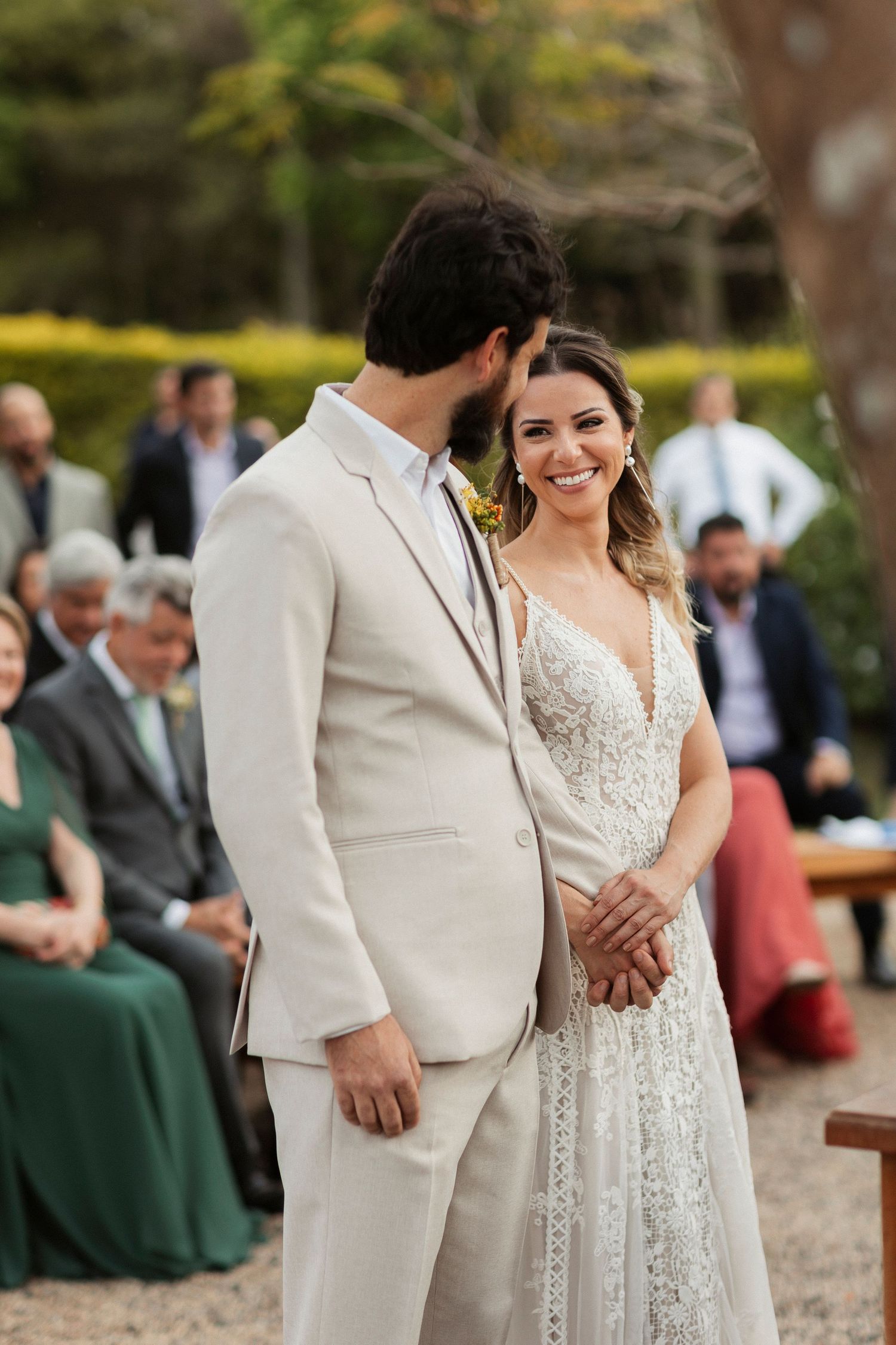 Couple sharing intimate moments during outdoor wedding ceremony with guests watching.