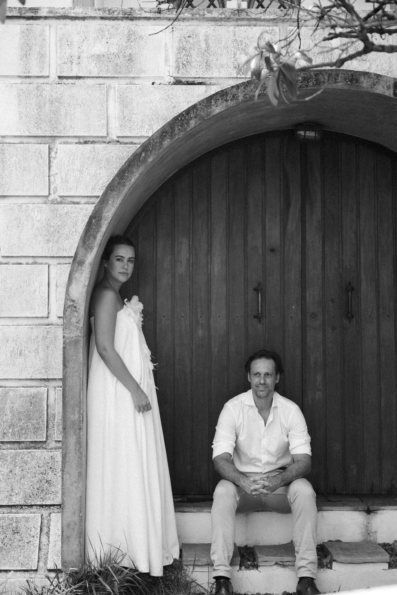 Stone archway with wooden door serves as rustic backdrop for wedding portraits.