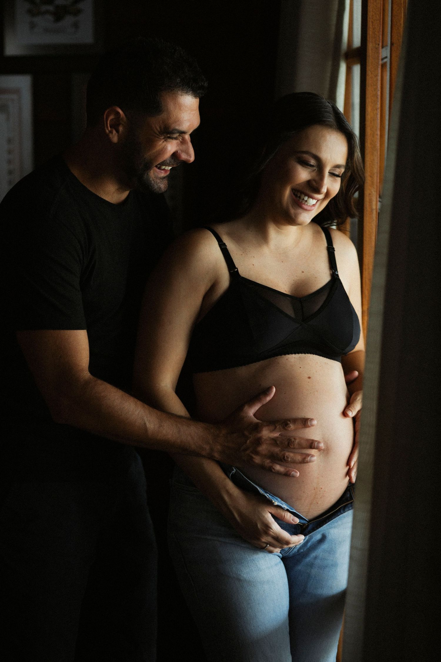 A series of intimate maternity photos showing a pregnant belly being cradled against a dark background.