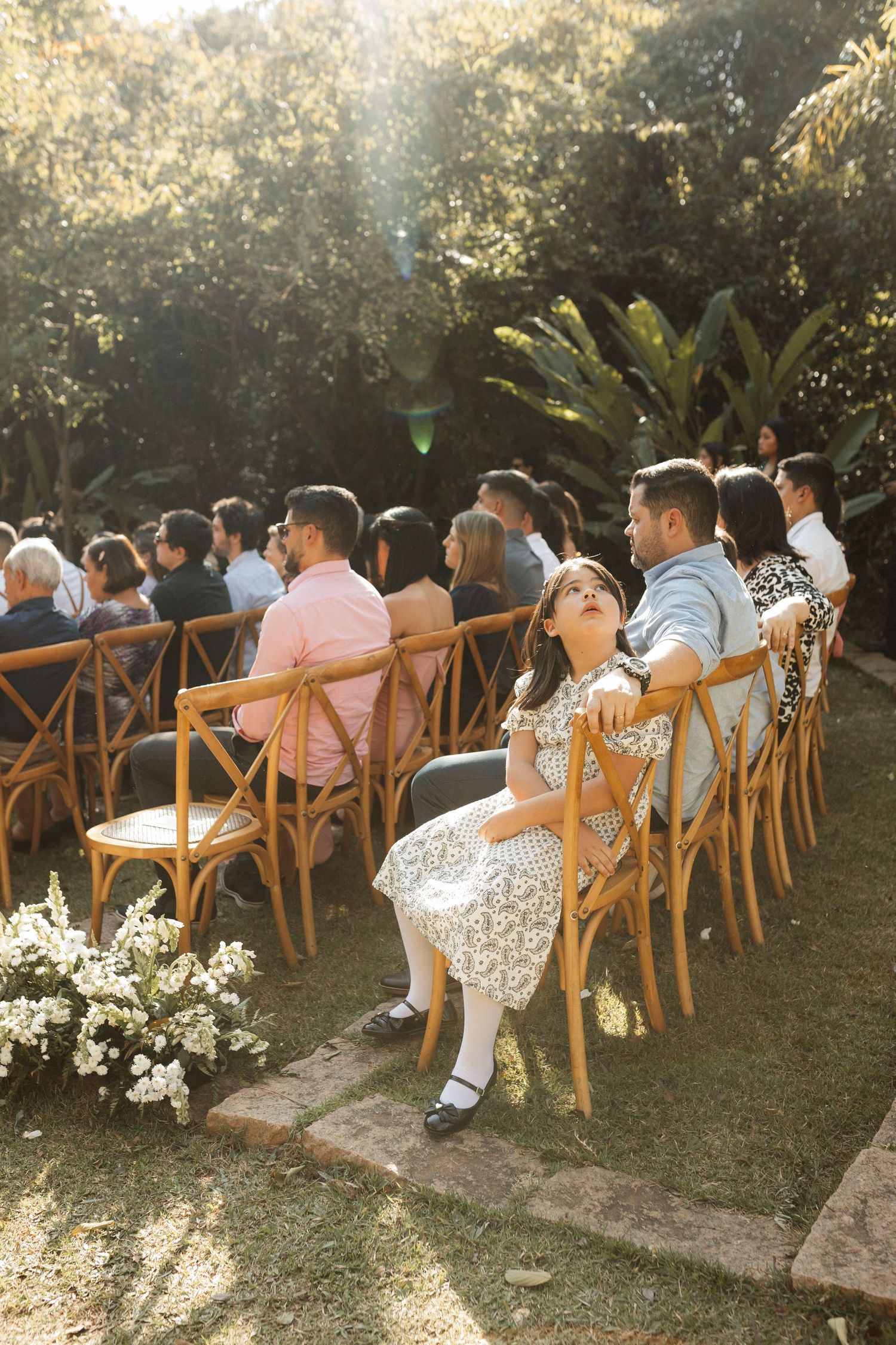 Outdoor wedding ceremony setup with wooden chairs and floral aisle decorations at sunset.