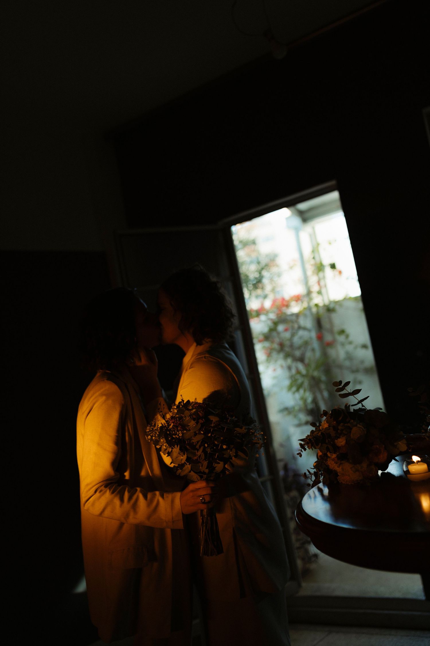 A moody indoor scene with warm lighting and flower bouquets creating a romantic atmosphere.
