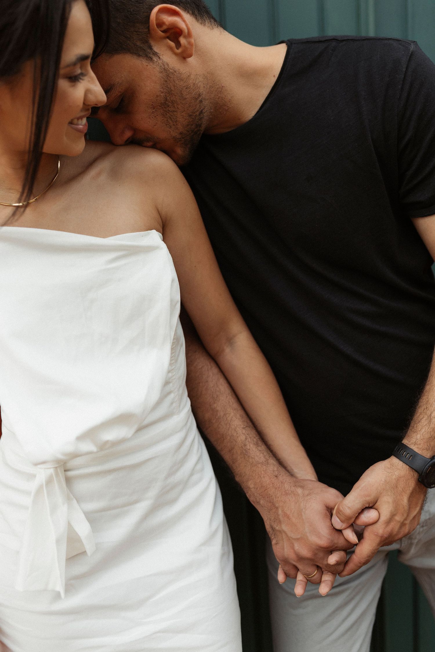 Detail shots of a couple in contrasting black and white outfits holding hands.