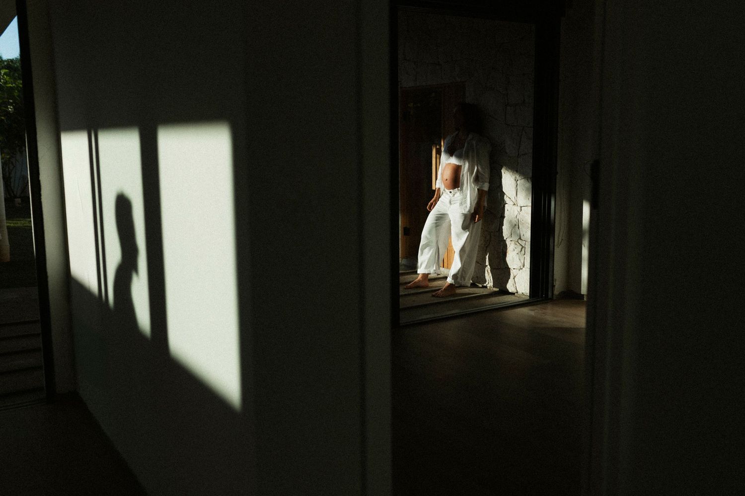 Couple sharing a romantic moment in a sunlit doorway with dramatic shadows on the wall.