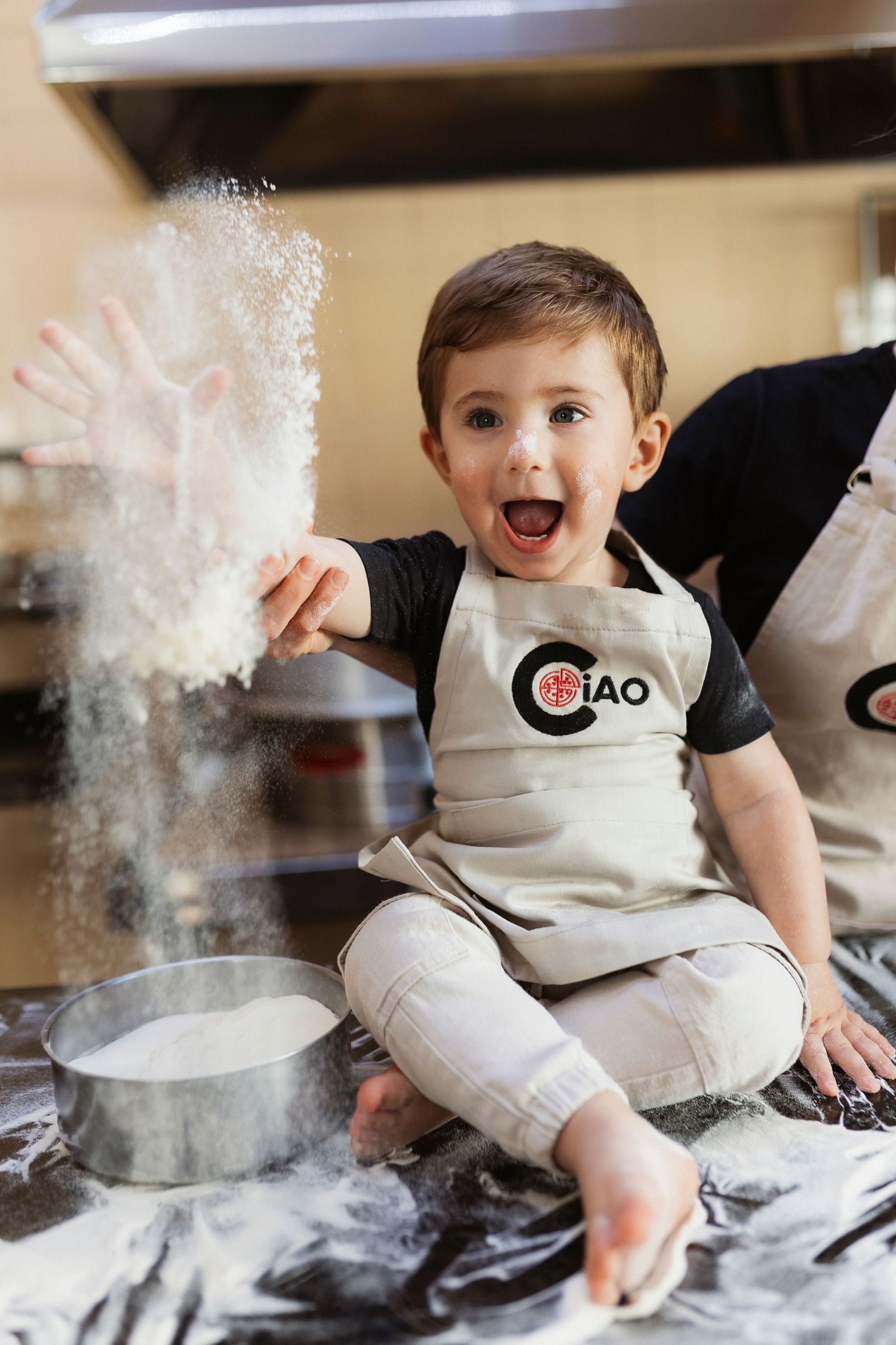 Young child playing with flour in kitchen creating messy but joyful baking scene.