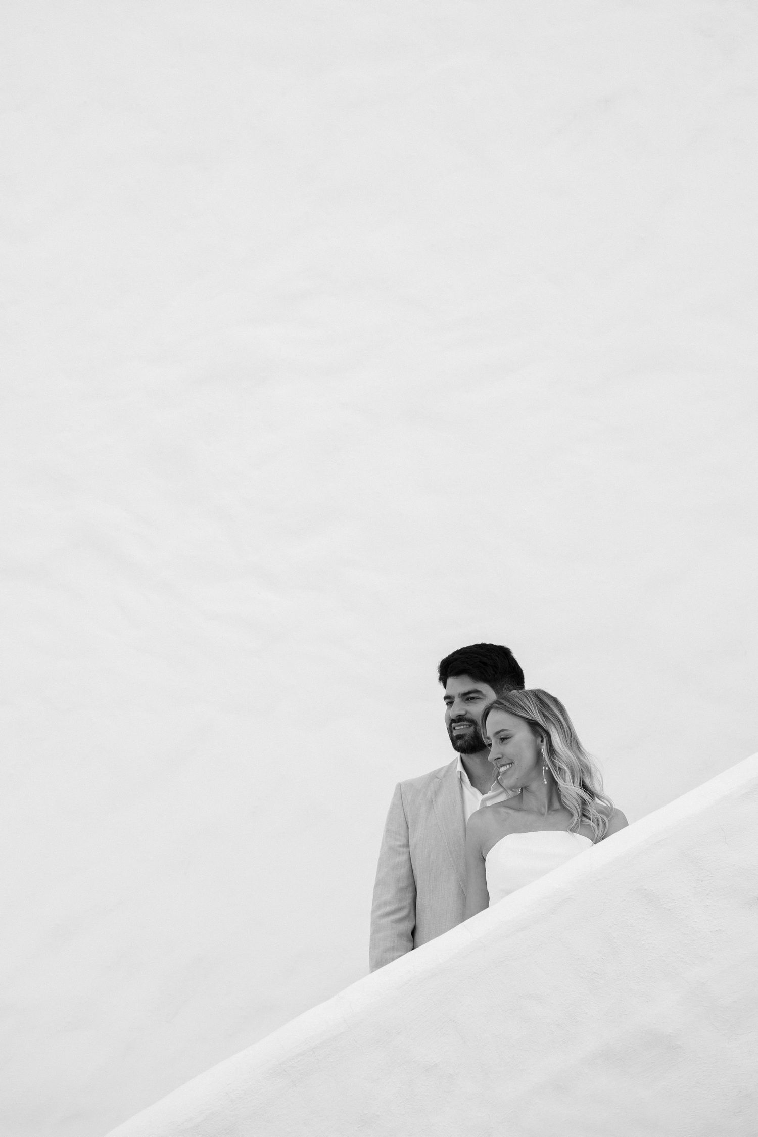 A minimalist black and white wedding portrait captured against a stark white background.