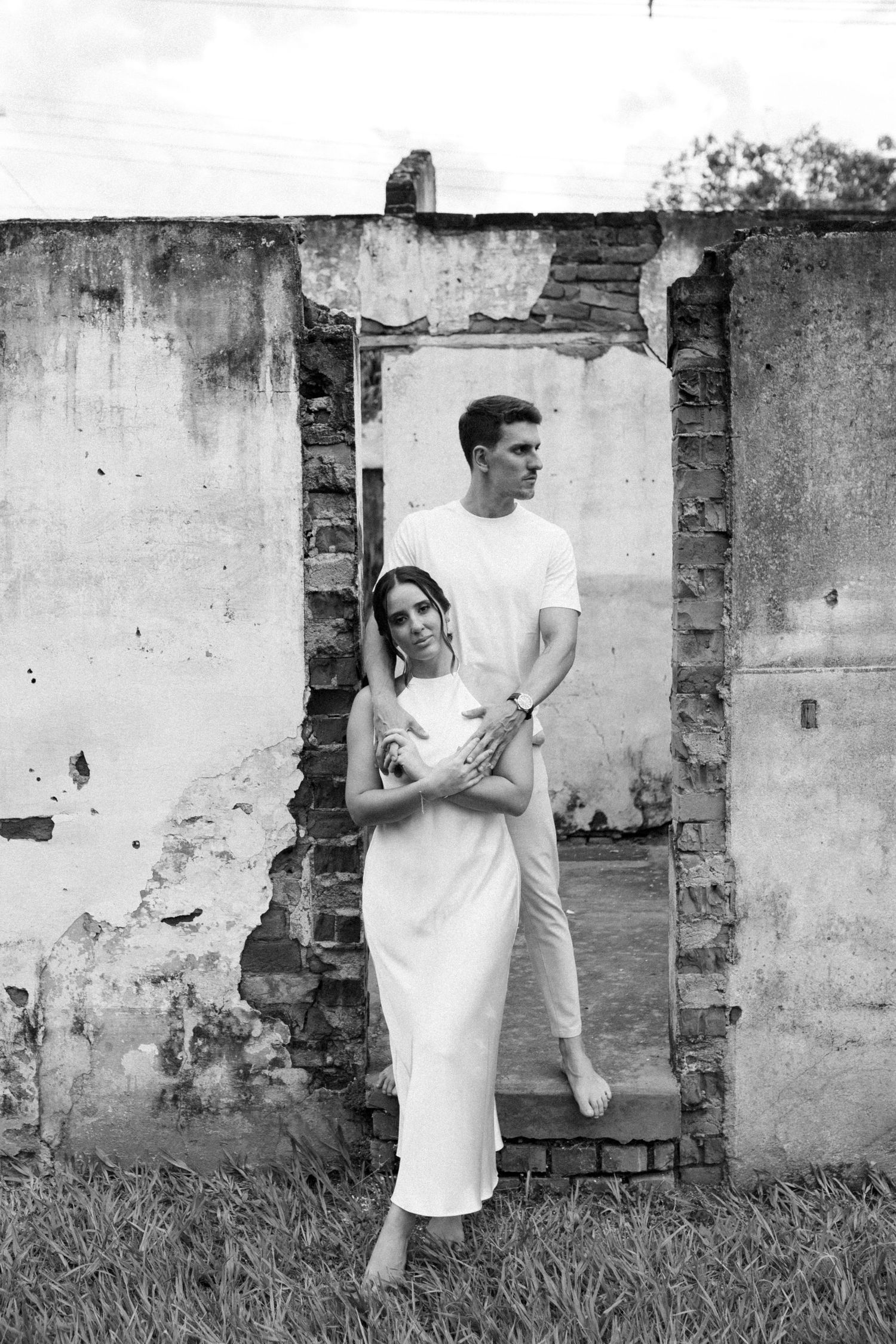 Artistic photo sequence of a couple in white outfits against old stone walls.