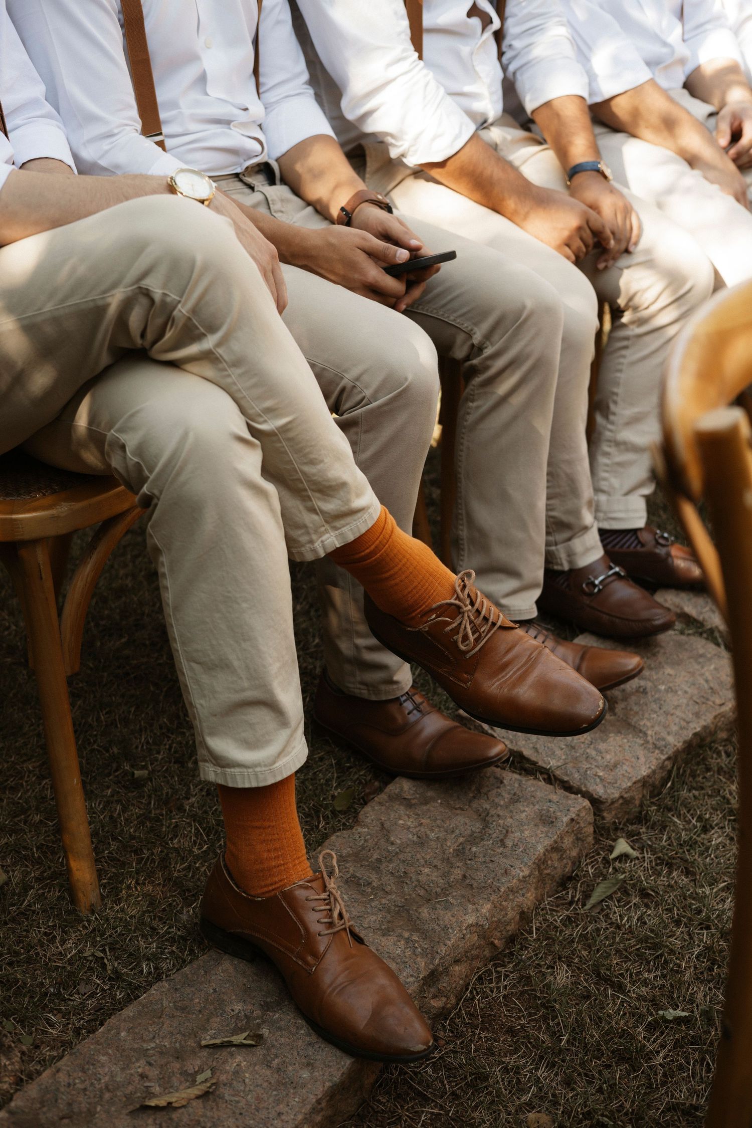 Groomsmen's coordinated brown leather shoes and orange socks detail shot.