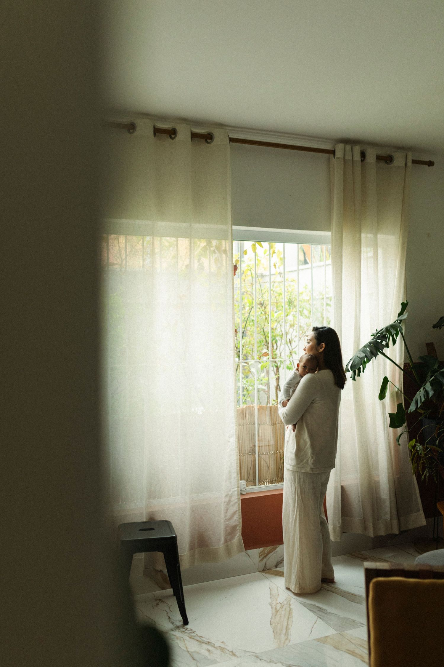 Sunlit room with flowing white curtains and indoor plants creating a serene atmosphere.