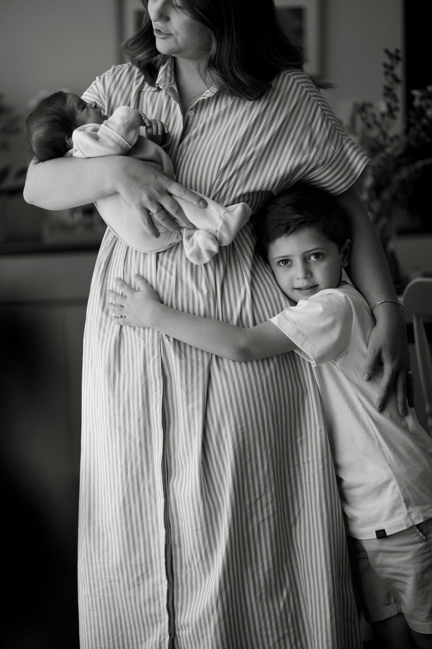 Black and white family portrait series showing playful interaction in a home setting.