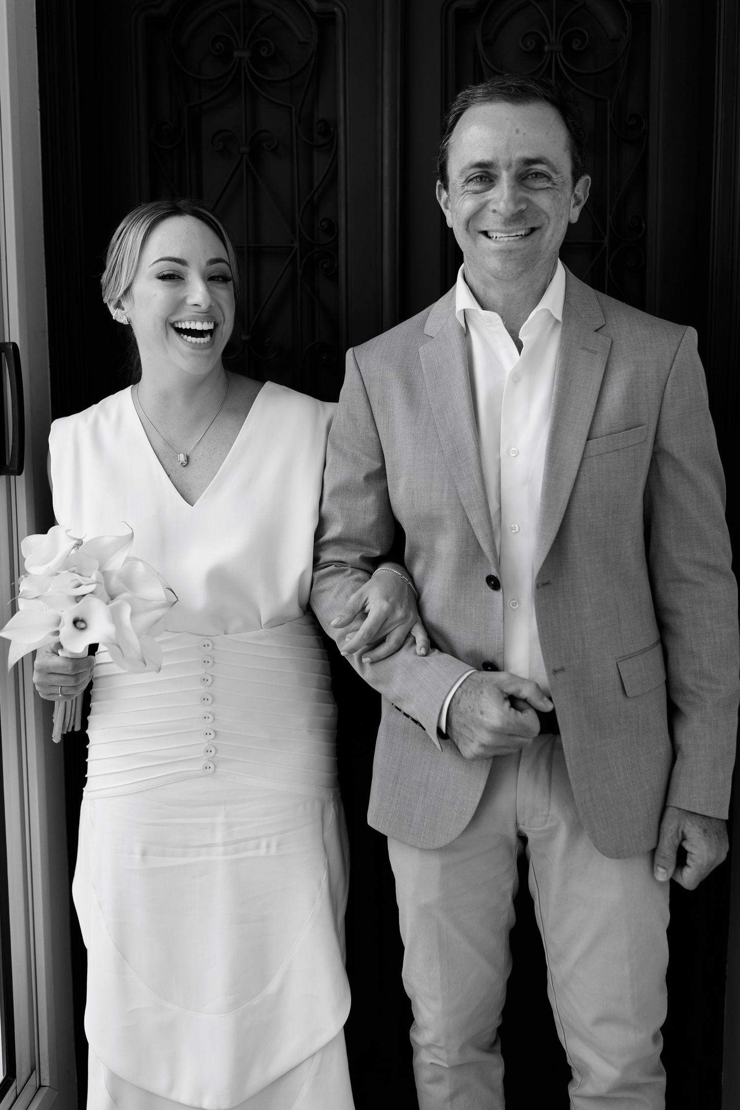 Black and white portrait of wedding couple smiling together in formal attire.