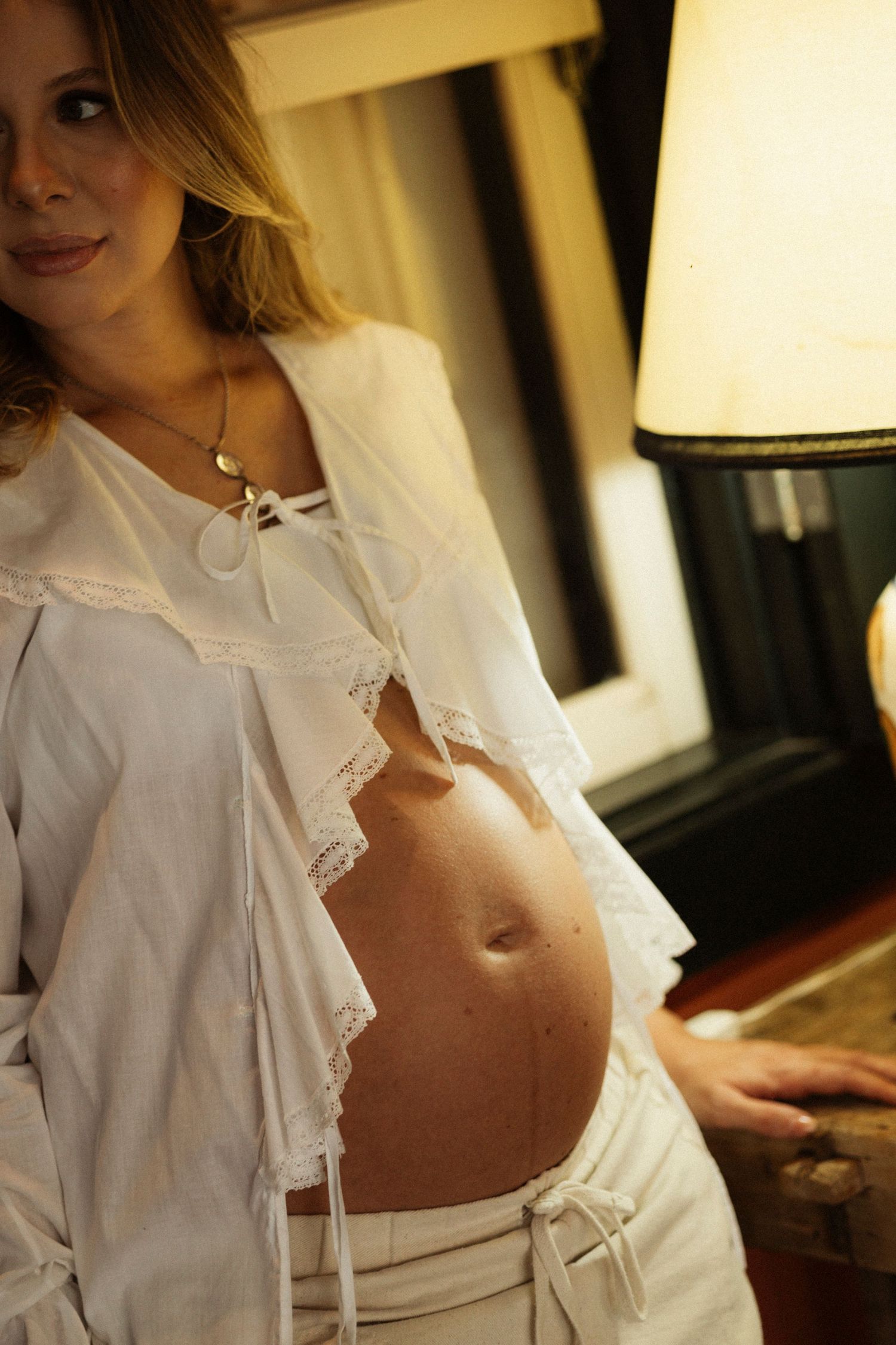 Maternity photo session featuring white lace clothing and warm lighting.