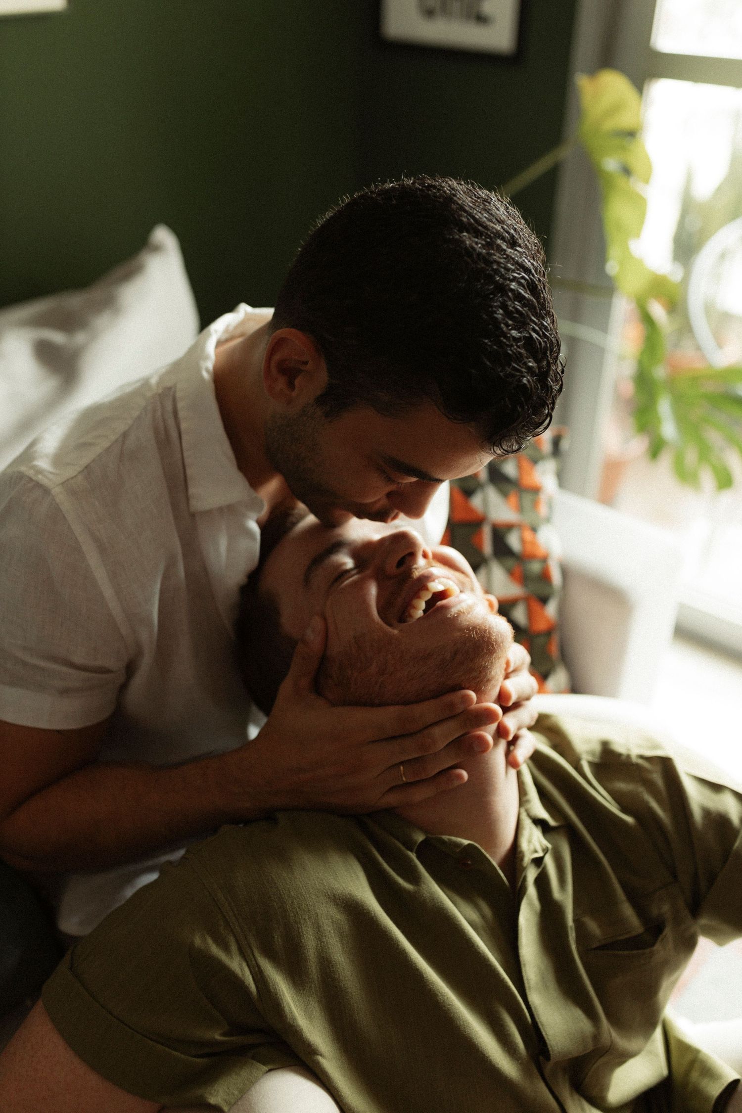 Two people share an intimate moment in soft natural lighting.