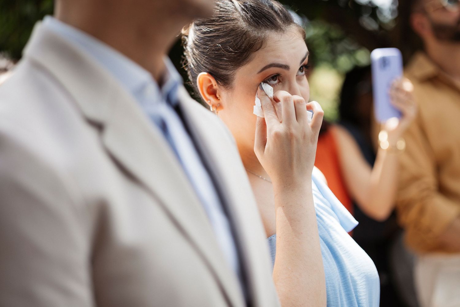 Wedding guests wiping tears during an emotional ceremony moment.