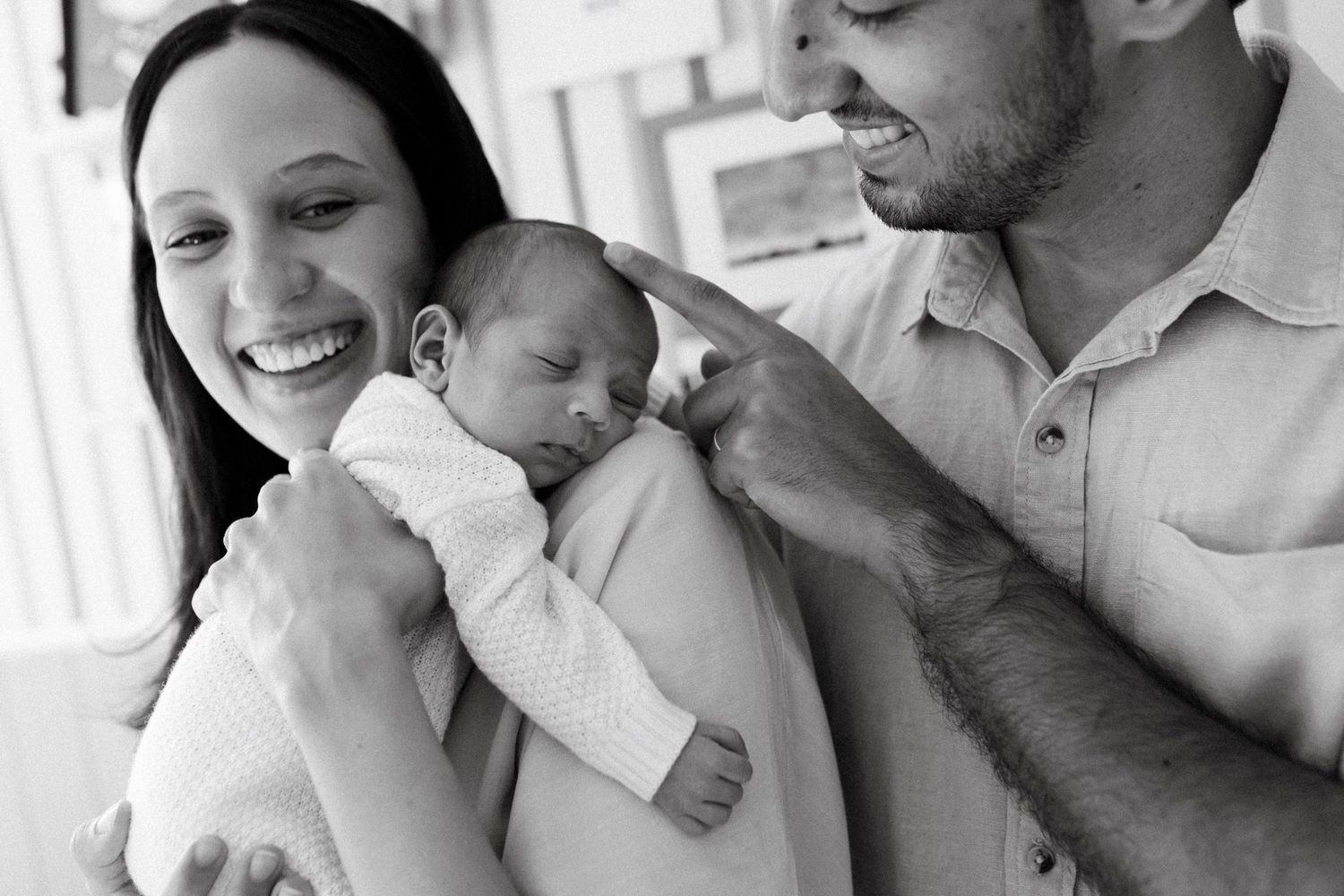 A series of black and white photos showing tender moments between parents and their newborn baby.