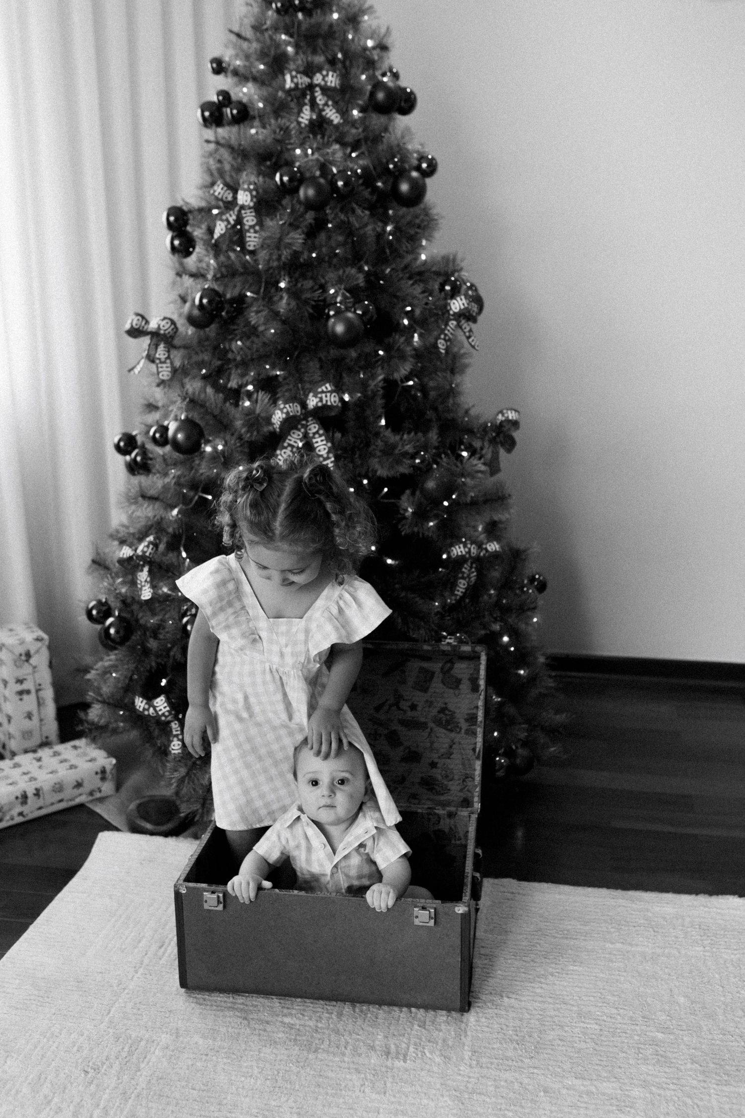 Black and white sequence of children playing near decorated Christmas tree.