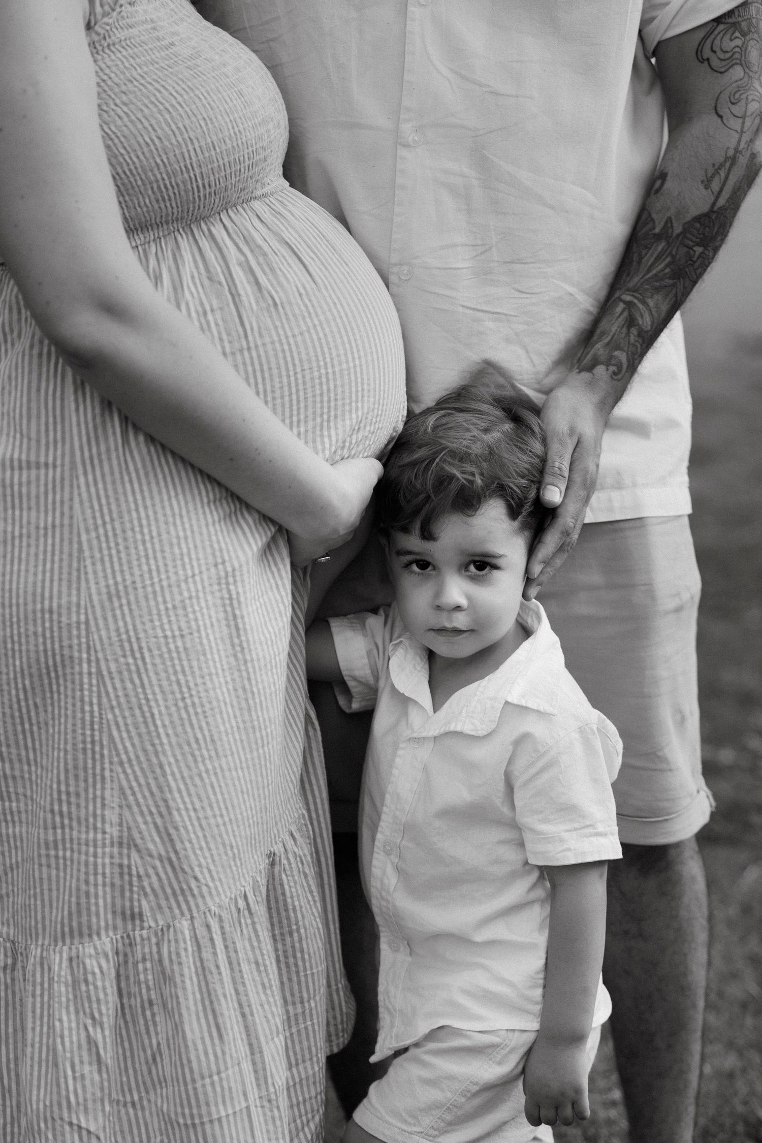 Family maternity photo sequence outdoors with cream dress and white clothing.