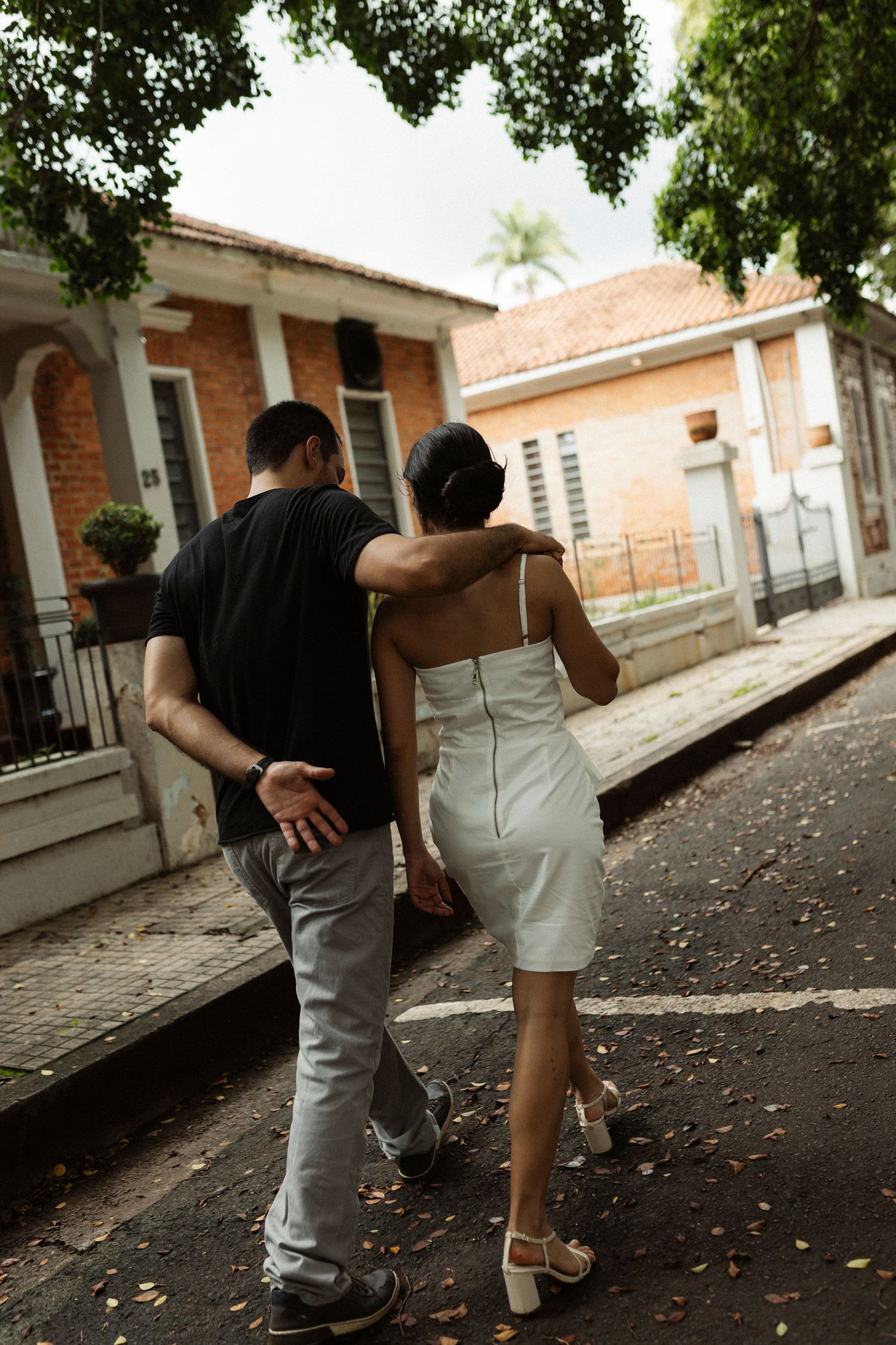 Couple walking together along a rustic colonial street with terracotta roofs.