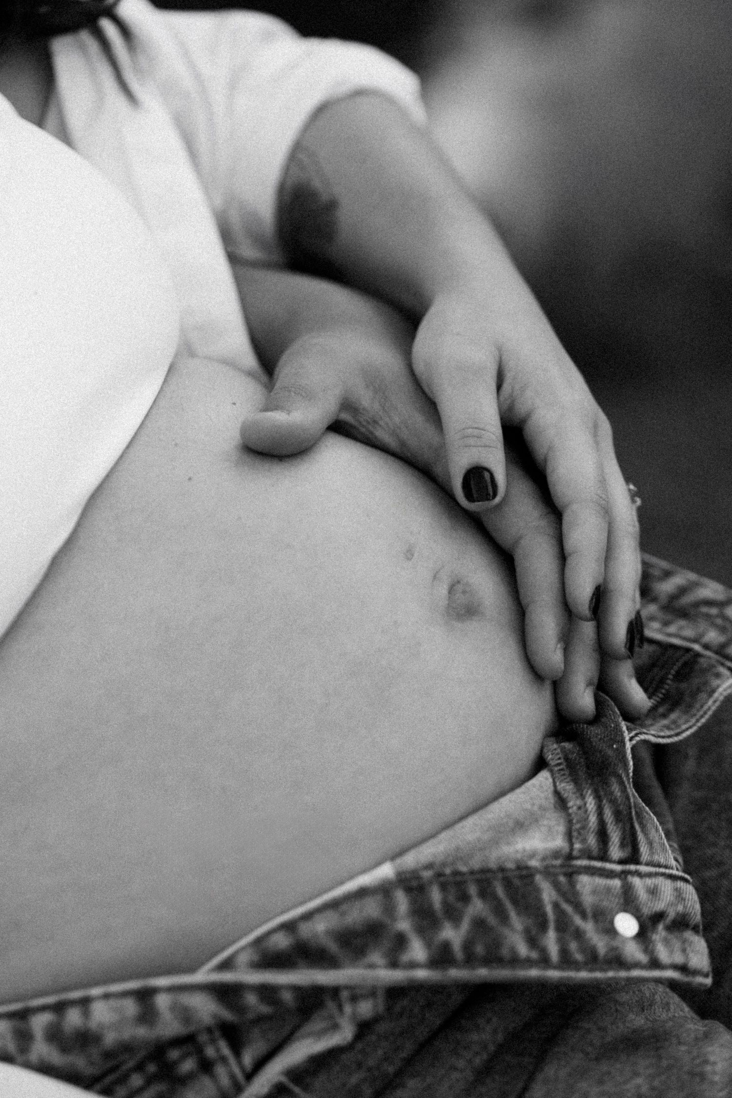 Close-up details of hands on denim in black and white photography.