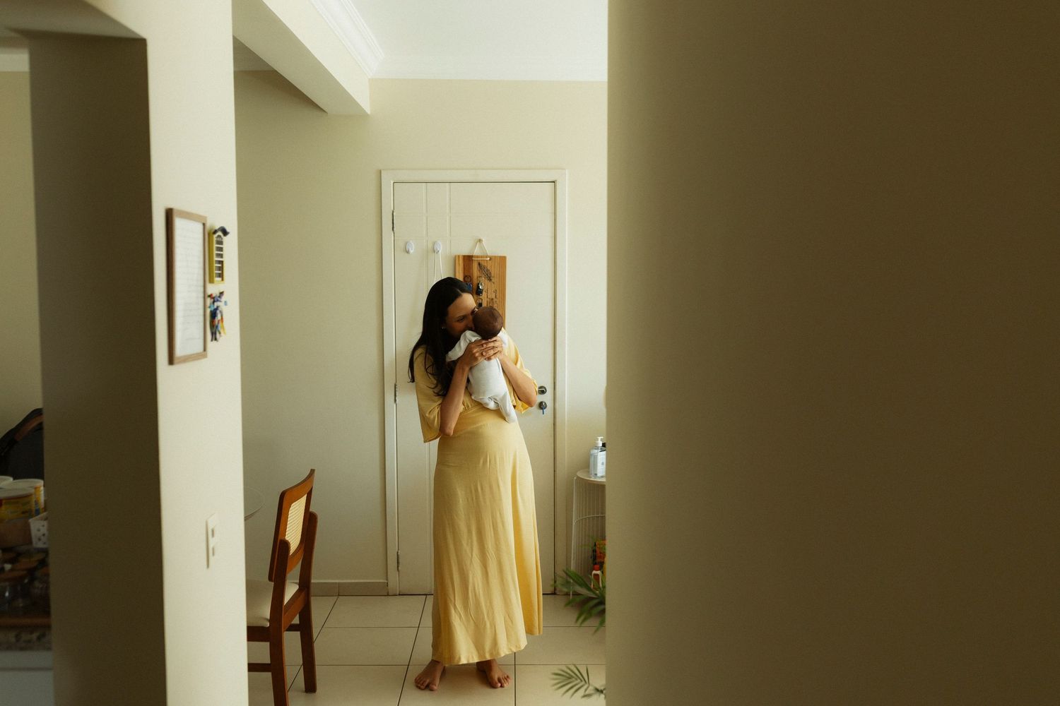 A person in a yellow dress stands in a bright hallway creating a series of dynamic mirror reflections.