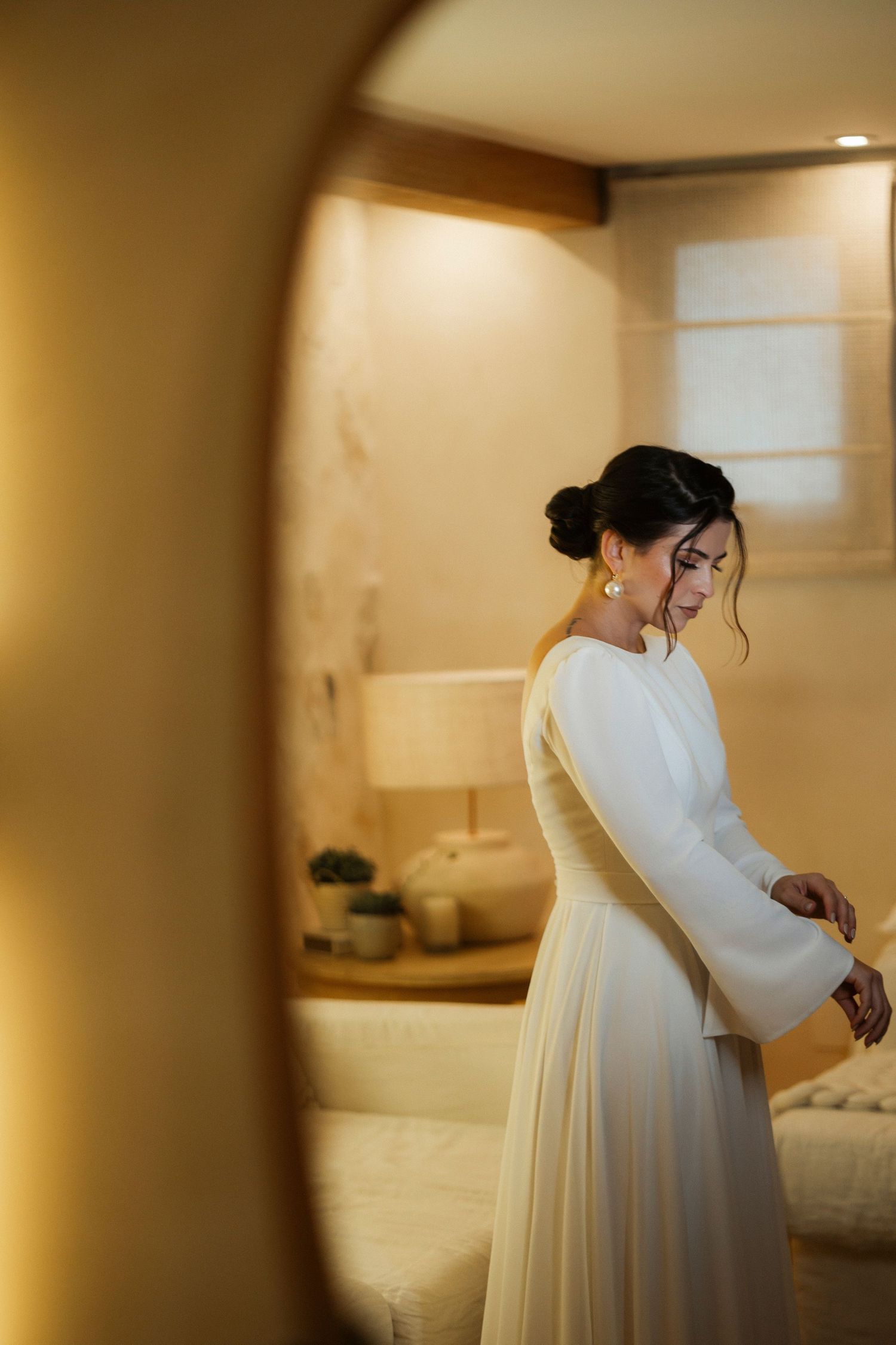 Intimate wedding moment captured in warm golden tones through doorway framing.