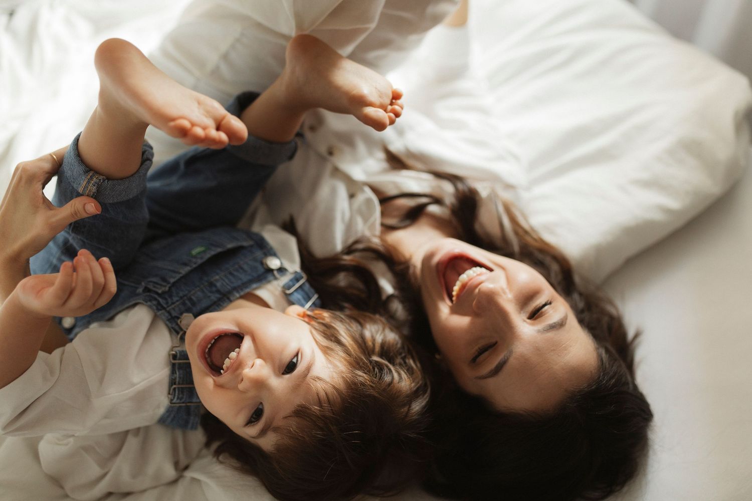 A series of candid black and white photos showing joyful moments on white bedding.